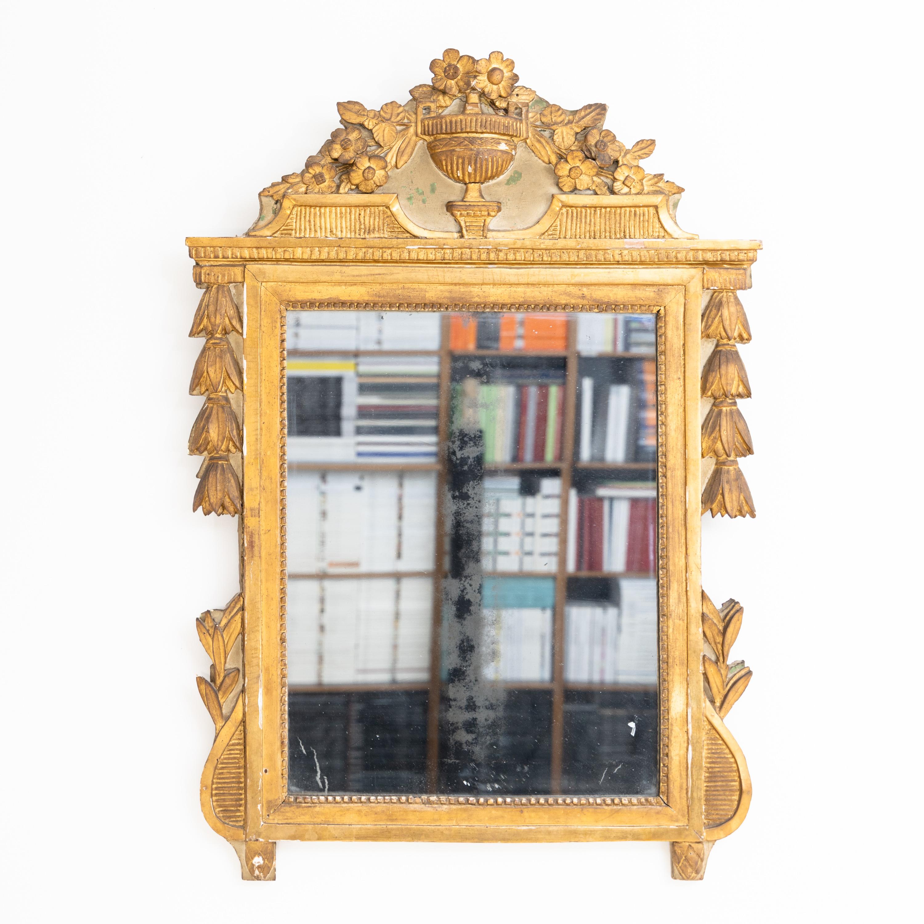 Wall mirror with amphorae and floral decoration in a carved, stuccoed and gold-patinated wooden frame. Gilding rubbed in places.