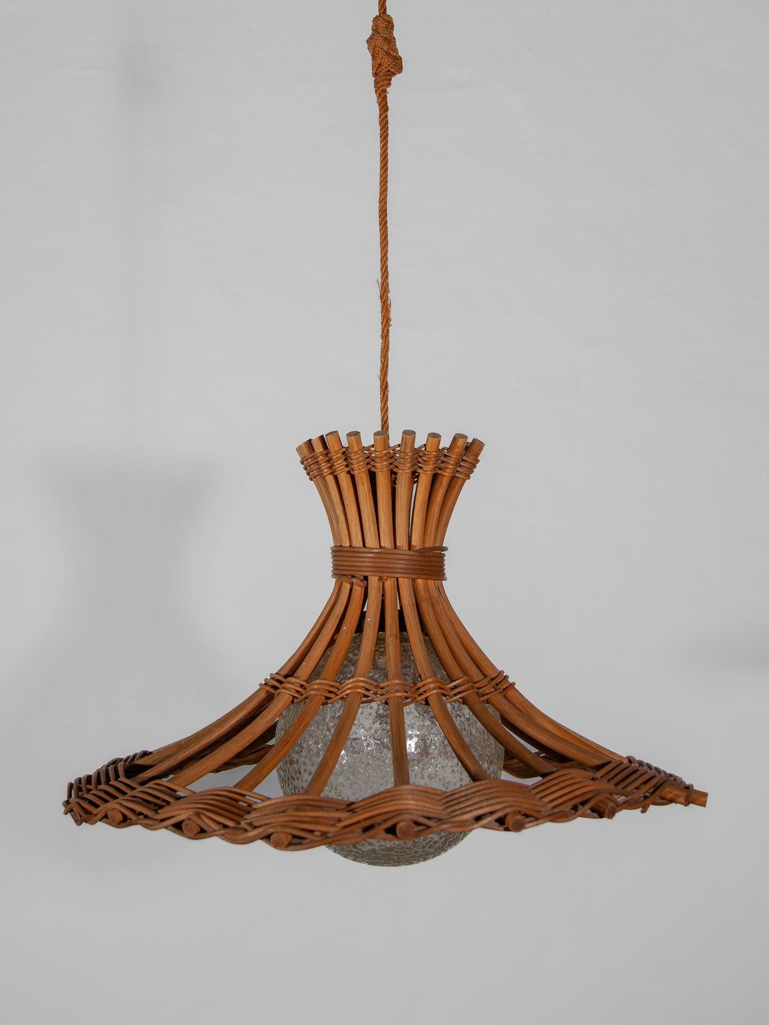 Ciondolo Boho-Chique di metà secolo con paralume in bambù e rattan e globo in vetro di Louis Sognot, Francia, anni '50. Questa bellissima lampada a sospensione è interamente realizzata a mano in bambù e rattan, con un cilindro centrale in vetro a
