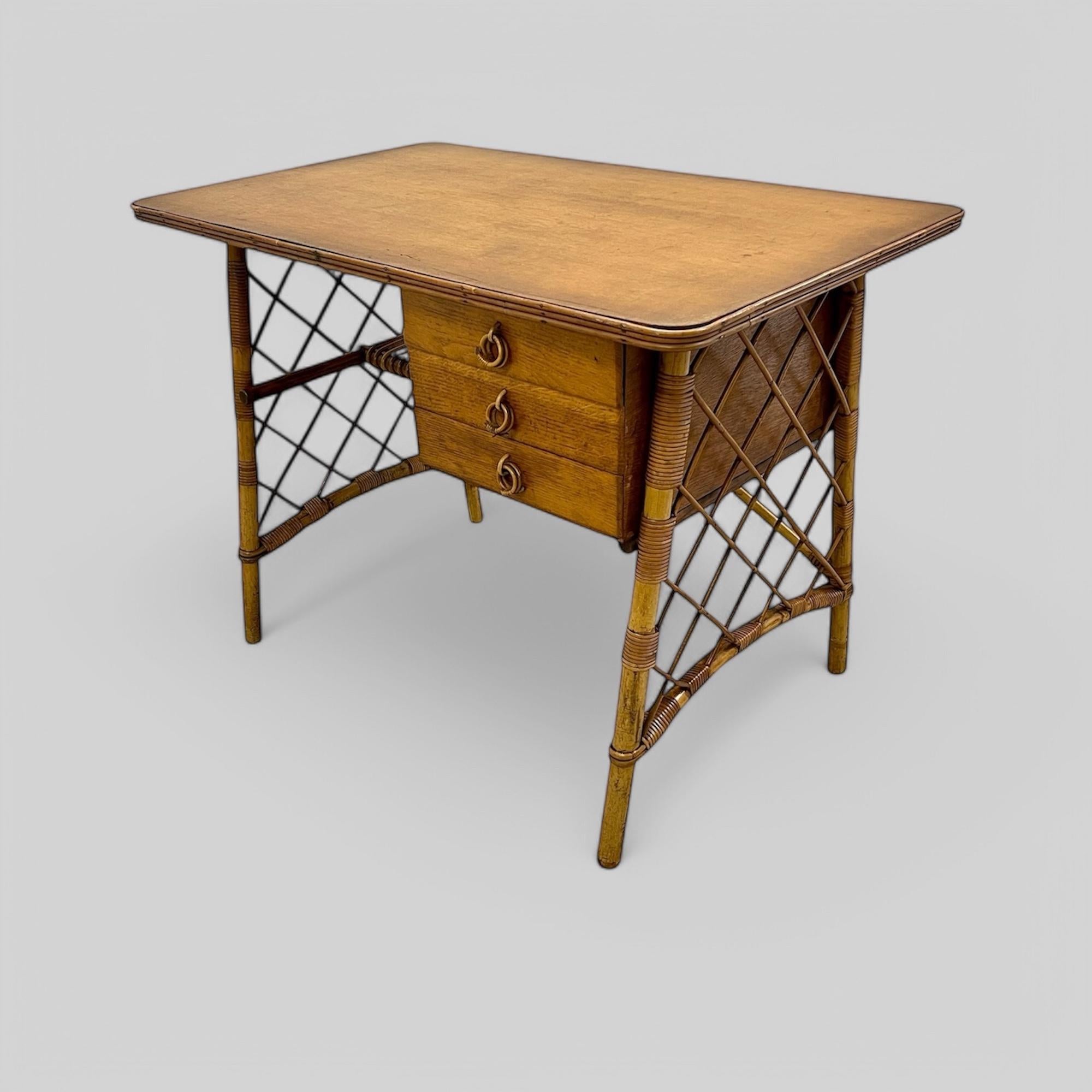 A Charming French Mid-Century Bamboo and Oak Desk or Dressing Table designed by Louis Sognot (1892-1970). This elegant piece features a solid oak top with an attractive reeded edge, resting on elegantly splayed bamboo legs adorned with lattice