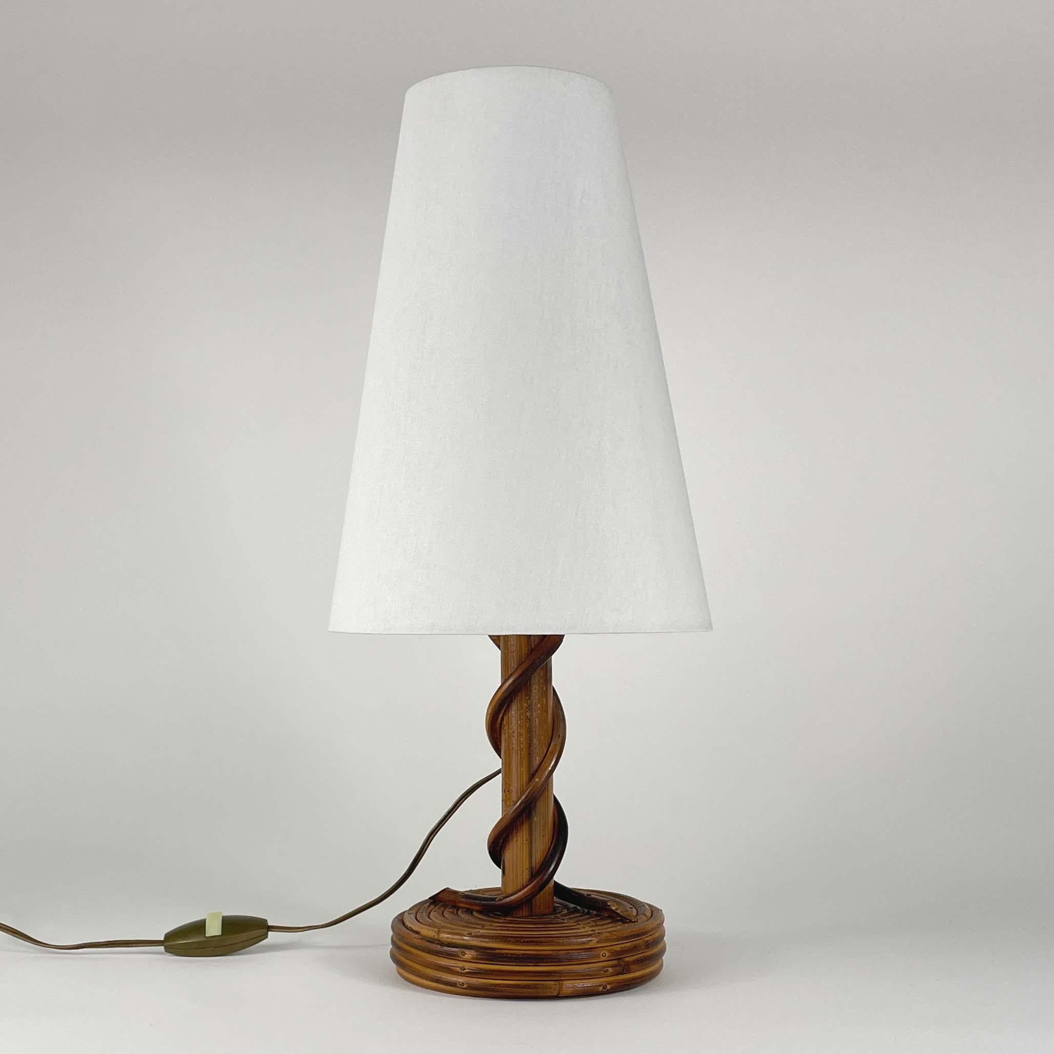 This beautiful table lamp was designed and manufactured by Louis Sognot in France in the 1950s. It features a bamboo and rattan base with off-white clip on conical shaped lampshade. The lampshade has been refurbished.

The light requires one E27