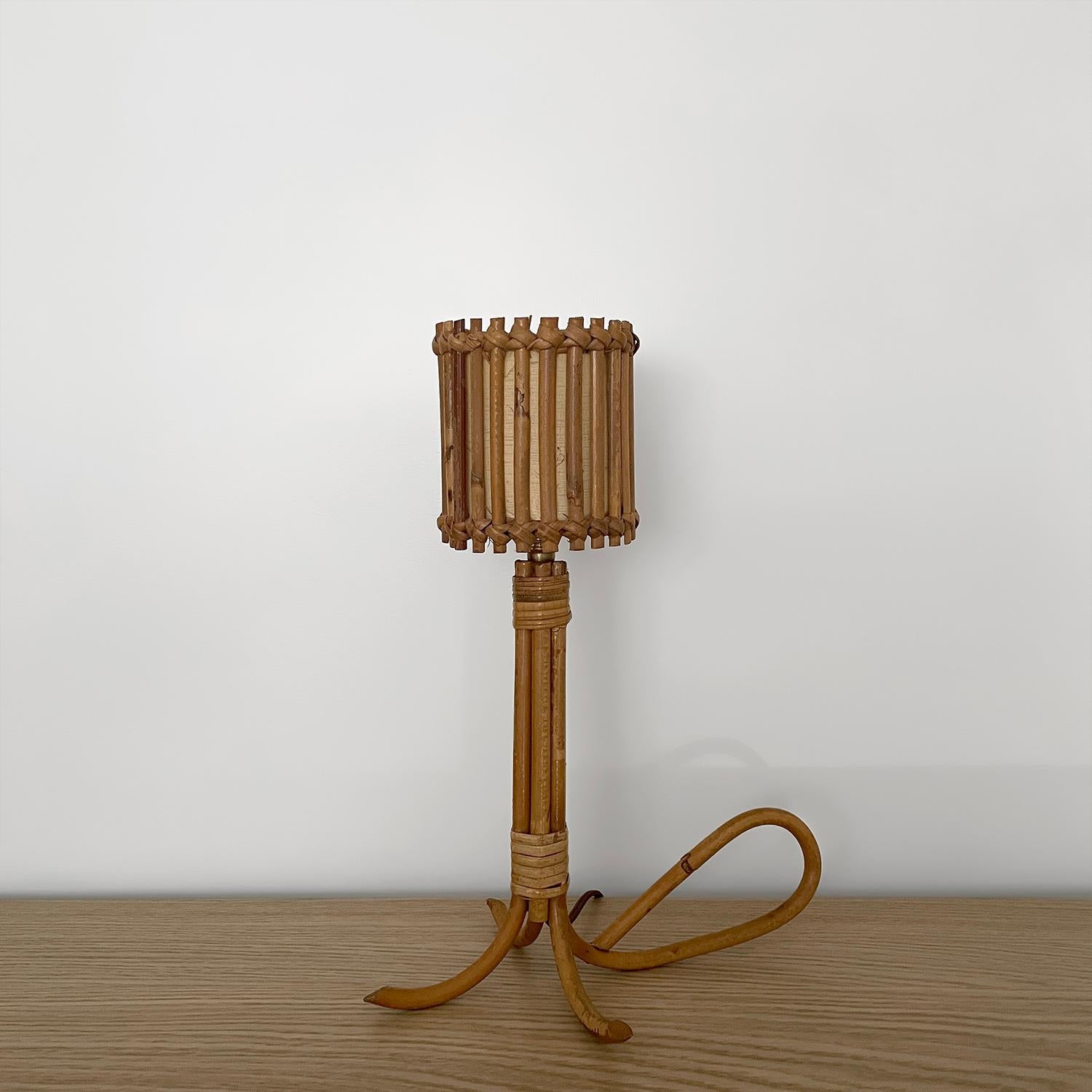 Louis Sognot French rattan lamp with loop base
France, circa 1960s
Handcrafted artisanal piece
Crisscross rattan reeds are intricately woven and encompass the drum shade 
Sculpted rattan base is finished with graceful loop detailing
Natural color