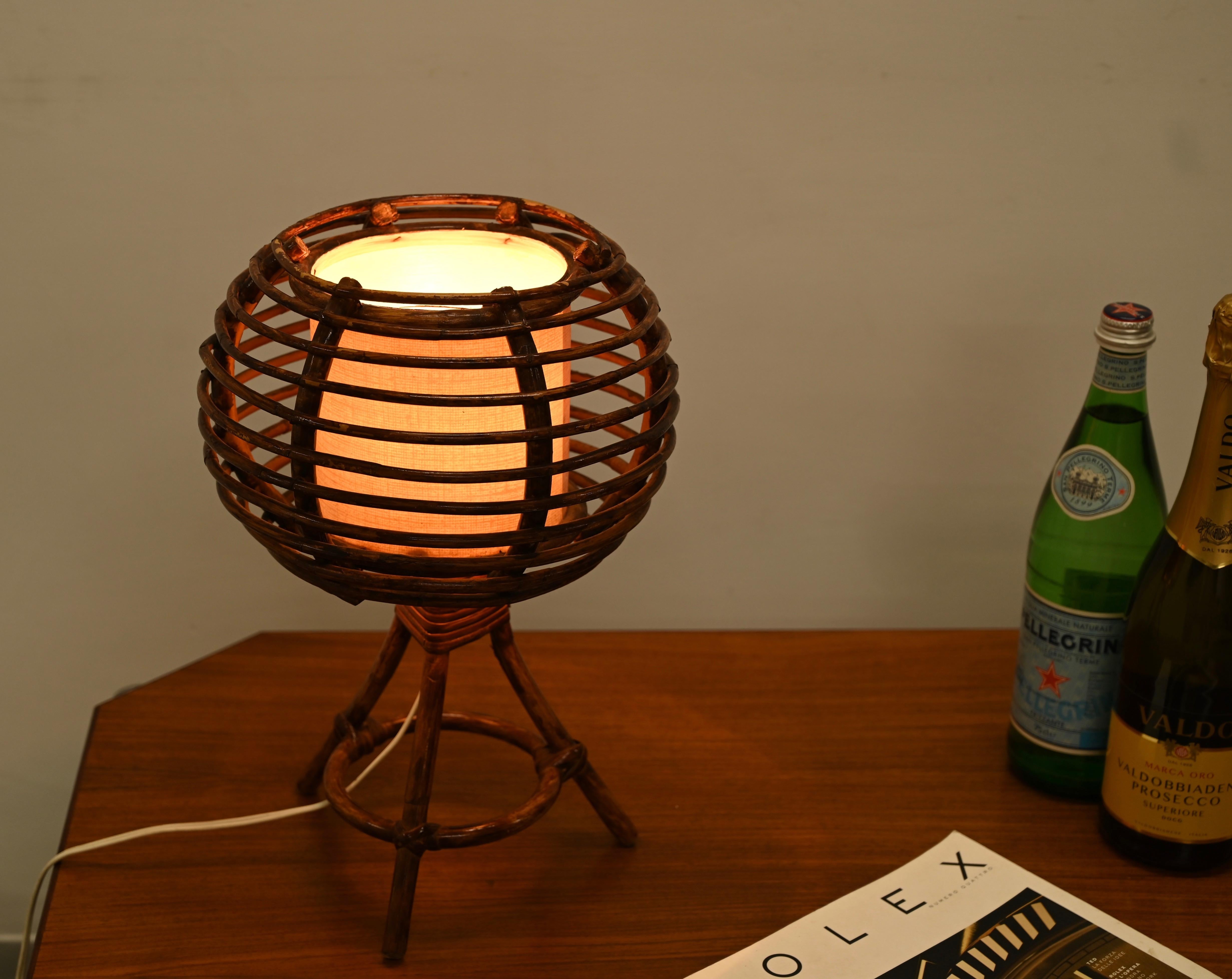 Lovely midcentury table lamp in curved rattan and wicker with a beige lampshade. This beautiful piece was made in France in the 1960s and is attributed to Louis Sognot.

The lamp features a clear example of '60s craftsmanship and organic design. A