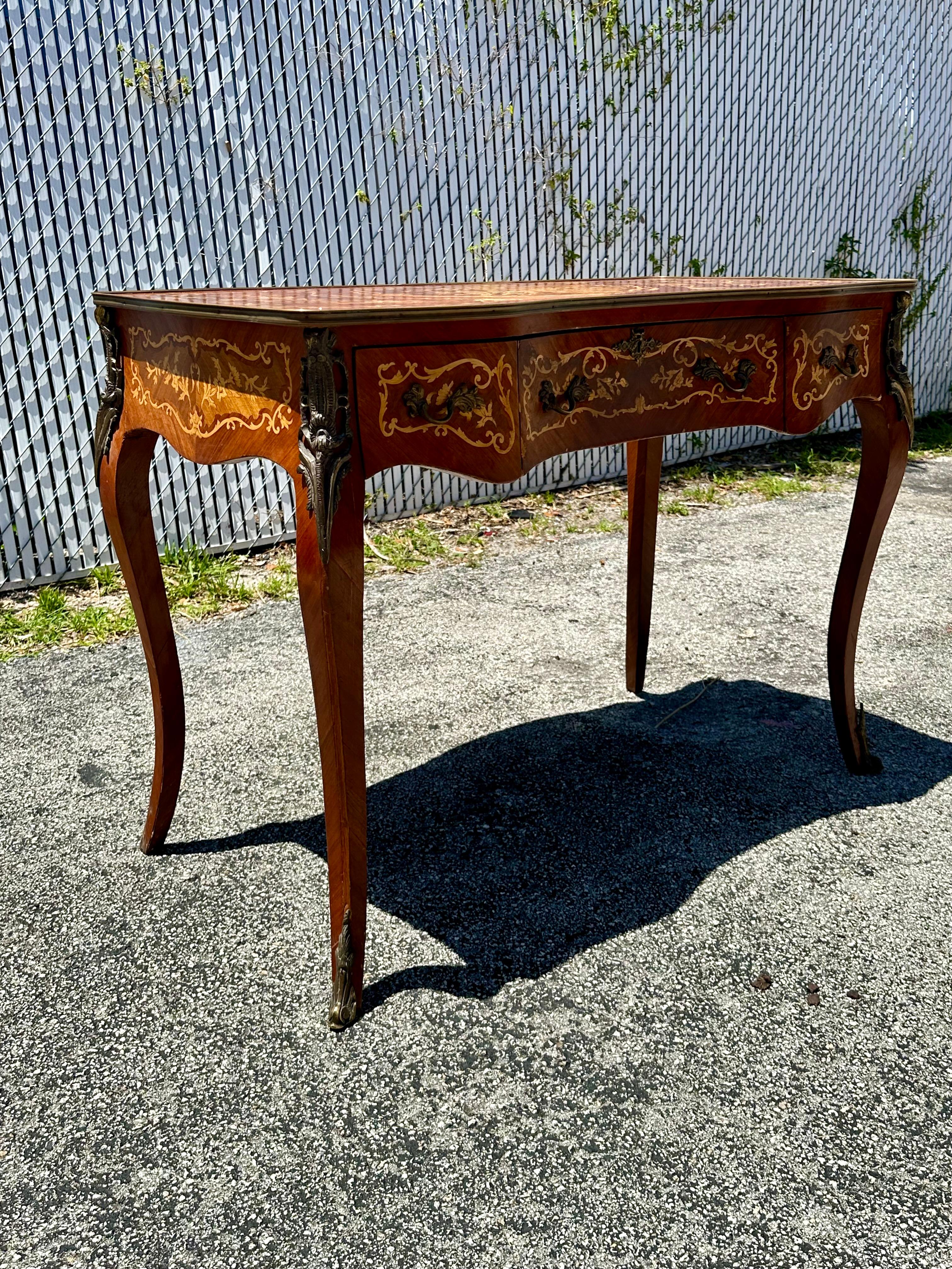 Trasportati nell'elegante e sofisticato inizio del XX secolo con questo squisito scrittoio Louis intarsiato con ferramenta in bronzo e ottone. La scrivania ultra rara emana un'aria di lusso e raffinatezza. Il design è eccezionale. La lussuosa