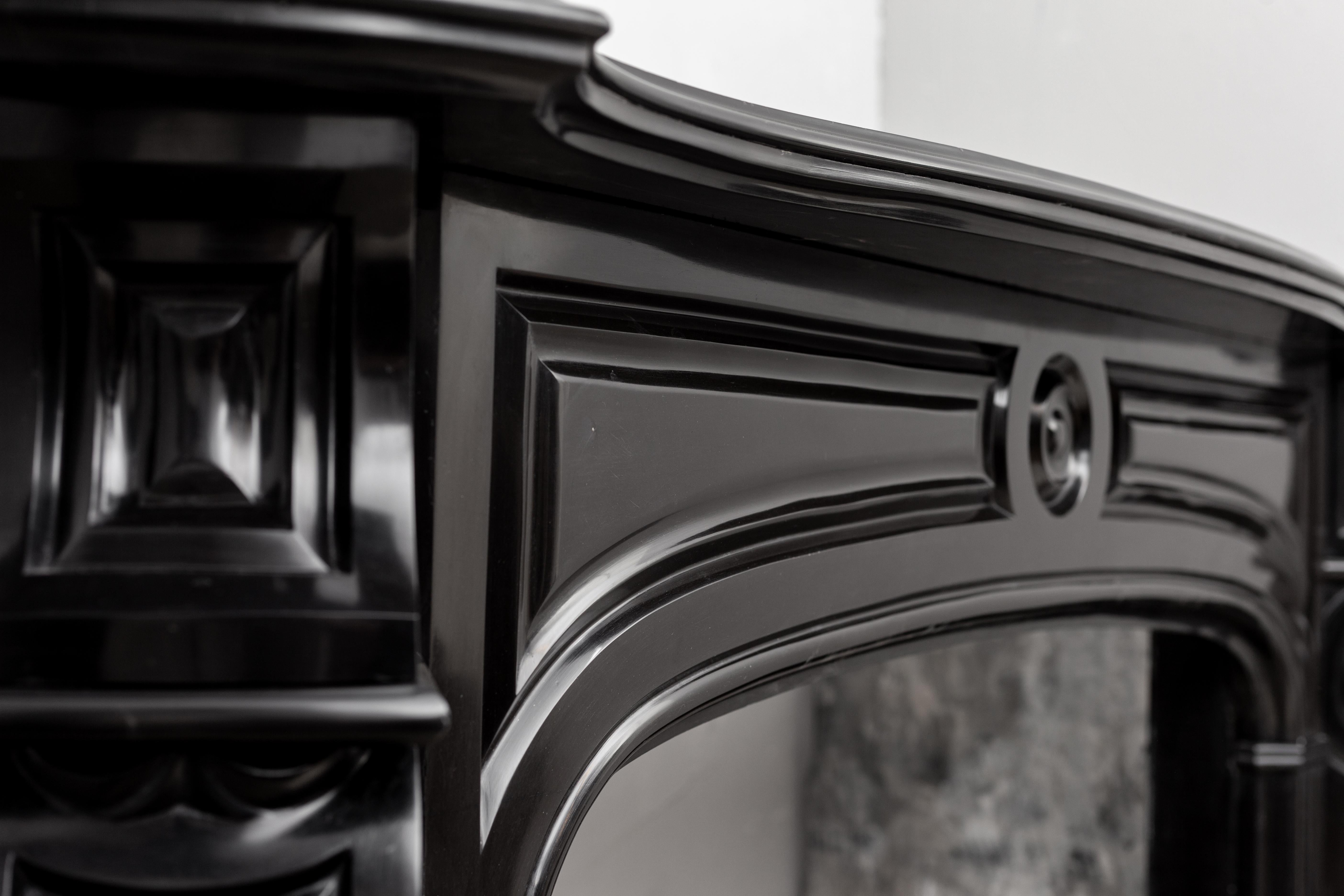 A magnificent marble fireplace wrapped in black marble: “Noir de Mazy”. An elegant combination of craftsmanship and distinctive styles. Everything about this mantelpiece is right, the round shapes of the decorated interior lintel make it a nostalgic