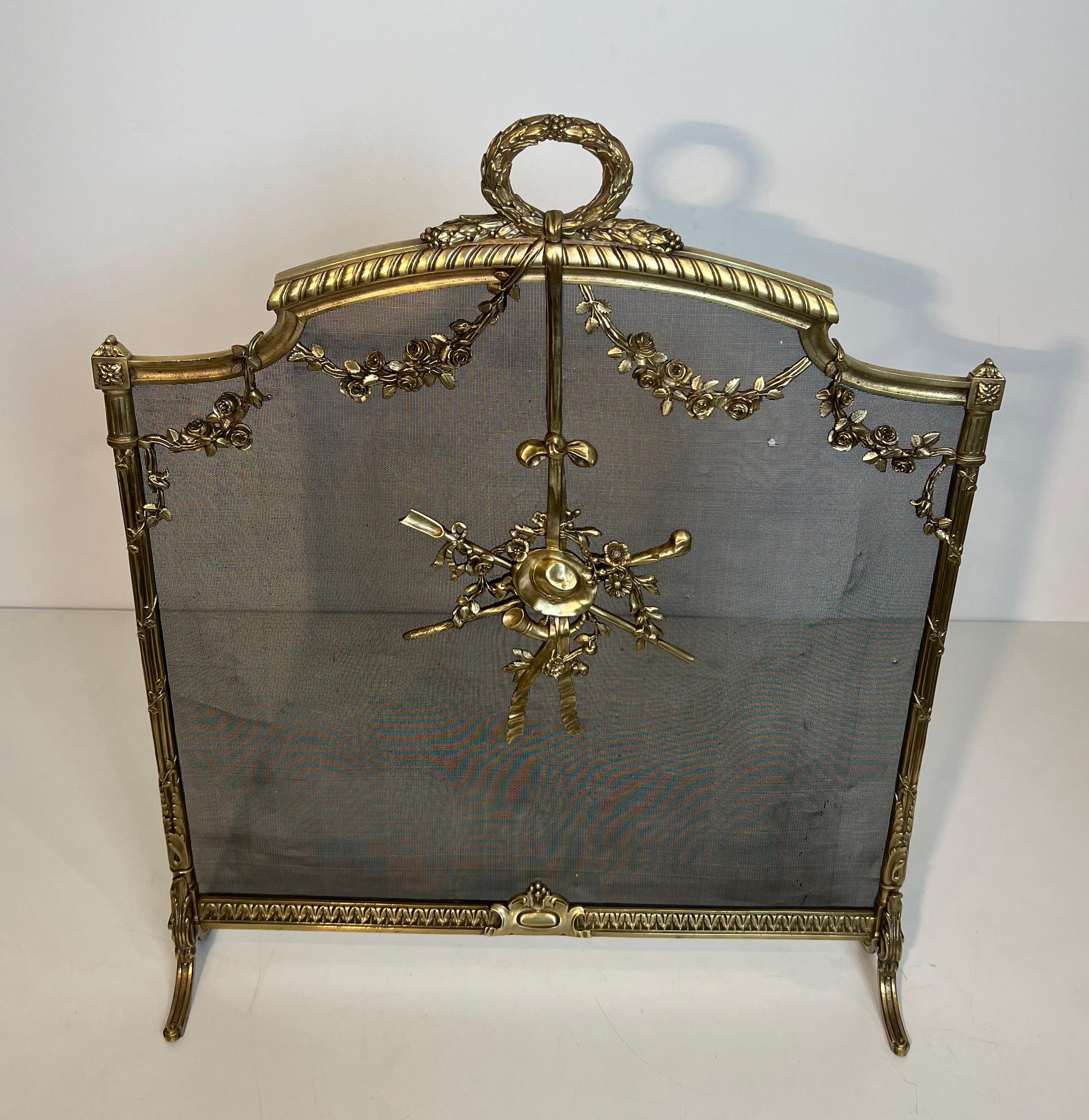 Questo paravento per caminetto molto bello è realizzato in ottone con rete ed è decorato con ghirlande, corona d'alloro, cappello e strumenti. Si tratta di un'opera francese nello stile di Luigi XVI. Circa 1940