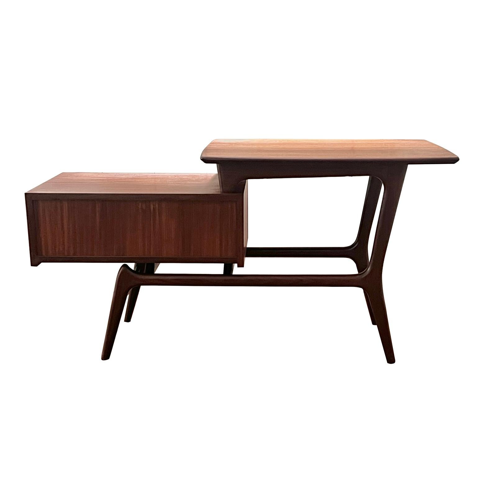 This side table called Nelly was designed in the 1960s by Louis Van Teeffelen for Wébé. It is made of oiled teak, with a storage cabinet with flap. This table is also used as a hall table. They are increasingly difficult to find and therefore a real