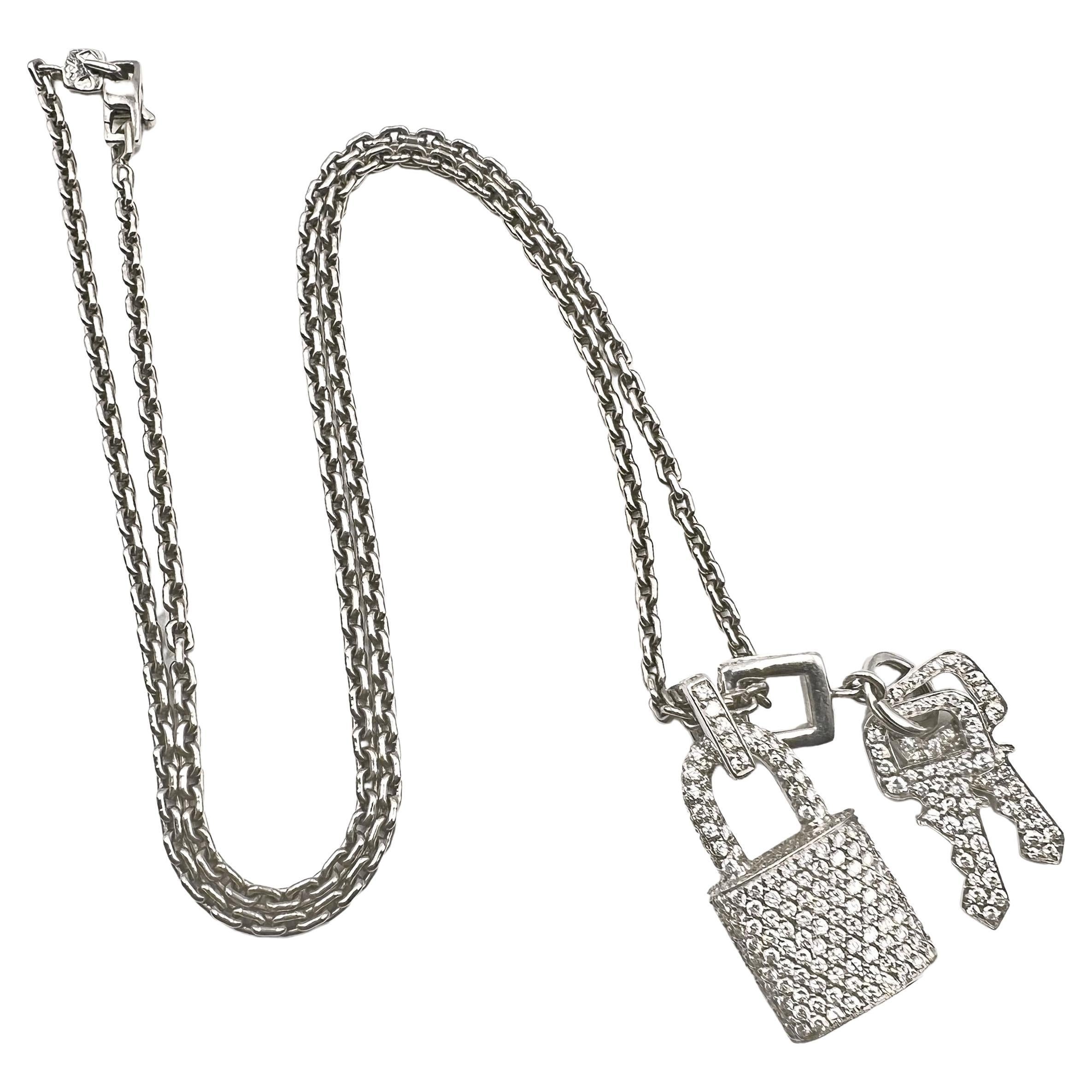 Two pendants by Louis Vuitton pave-set with round brilliant-cut diamonds throughout.   The miniature lock pendant has a square form bail with a 