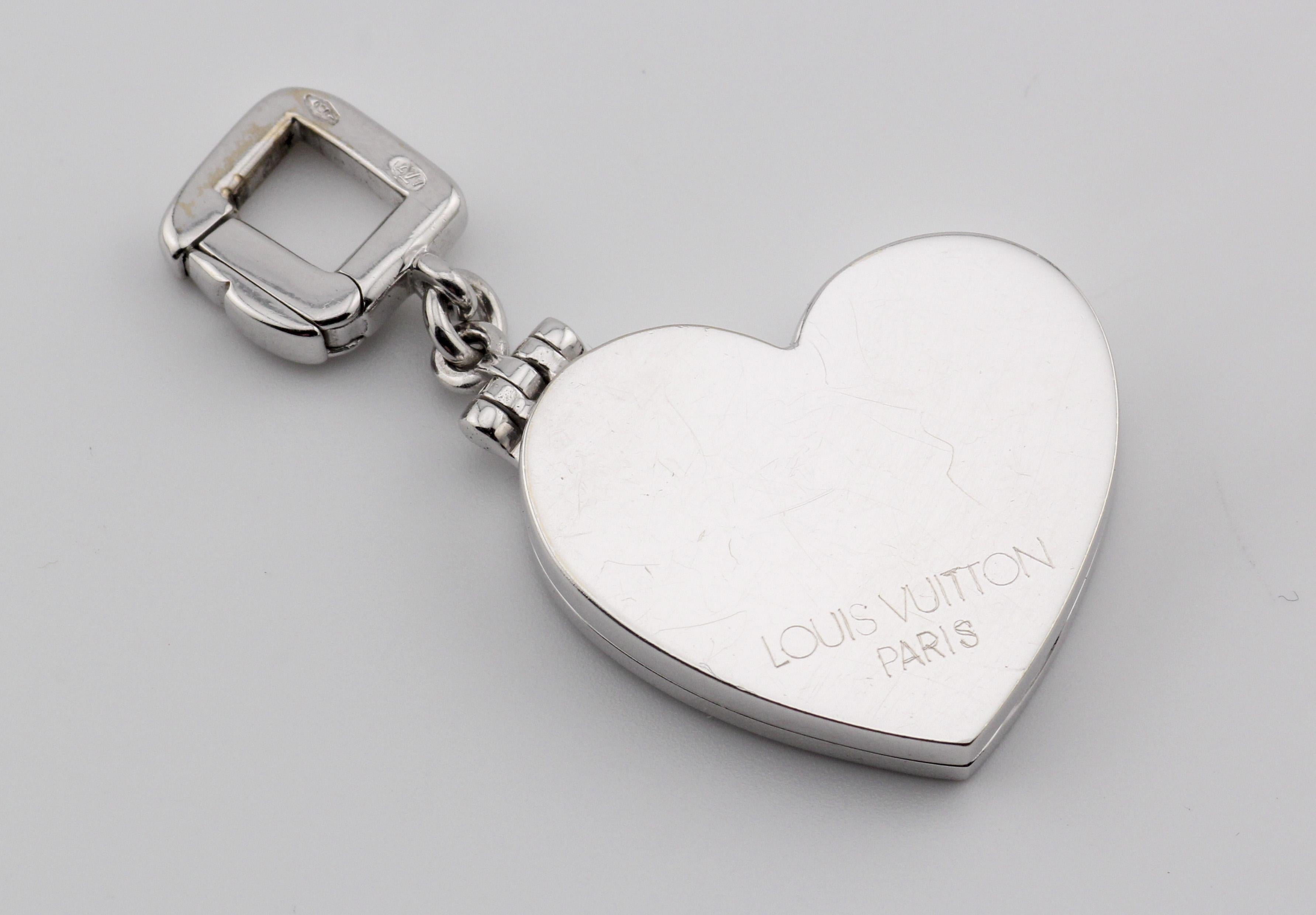 The Louis Vuitton 18K White Gold Heart Locket Charm Pendant is a captivating and luxurious piece that seamlessly combines timeless elegance with modern design. Crafted with precision and attention to detail, this exquisite charm pendant reflects the