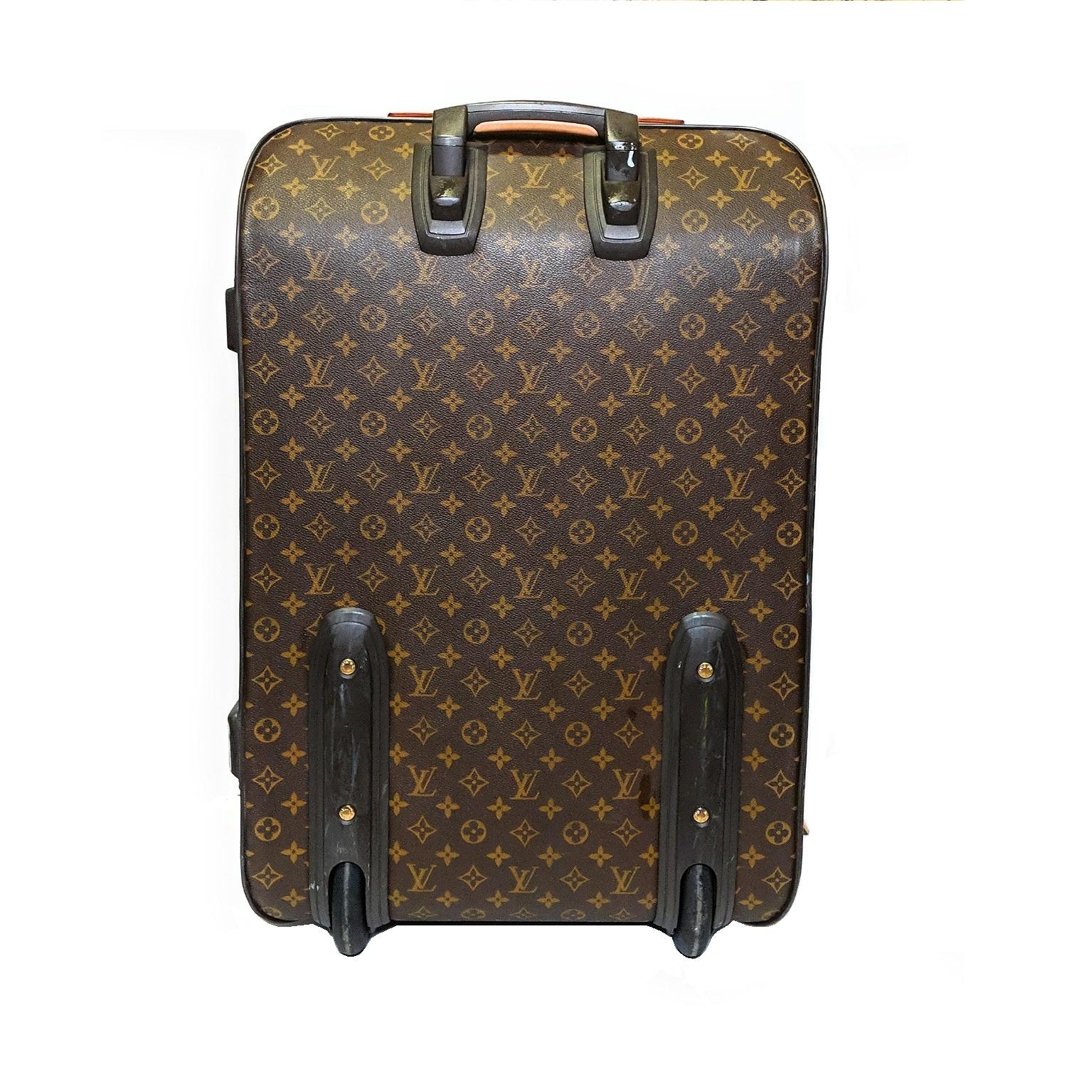 Brown and tan monogram coated canvas Louis Vuitton Pégase 65 with brass hardware, tan Vachetta leather trim, flat handles at top and side, retractable pull-handle at top, single exterior zip pocket at front, dual wheels and protective feet at base,