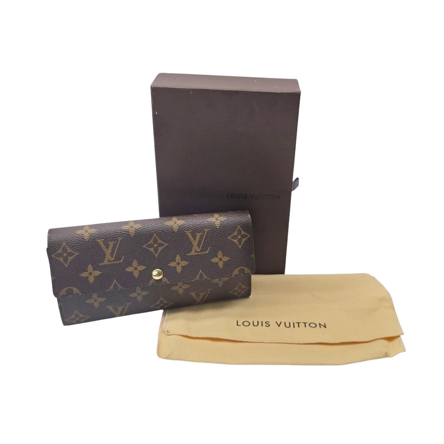 Questo portafoglio Louis Vuitton Monogram Porte-Monnaie è realizzato in tradizionale tela rivestita con monogram, con una mezza patta frontale che si apre con un bottone a pressione e un interno in pelle martellata color terracotta con una sezione
