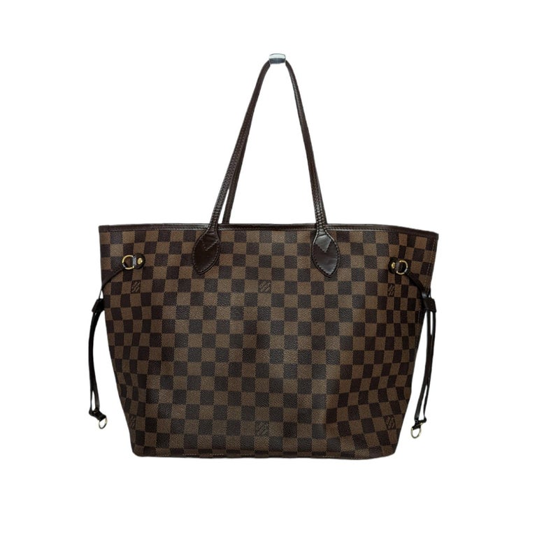 This chic handbag is crafted of classic Louis Vuitton Damier coated canvas in brown. The bag features chocolate brown cowhide leather shoulder straps, side cinch cords, and trim, with polished brass hardware. The top is open to a striped red fabric
