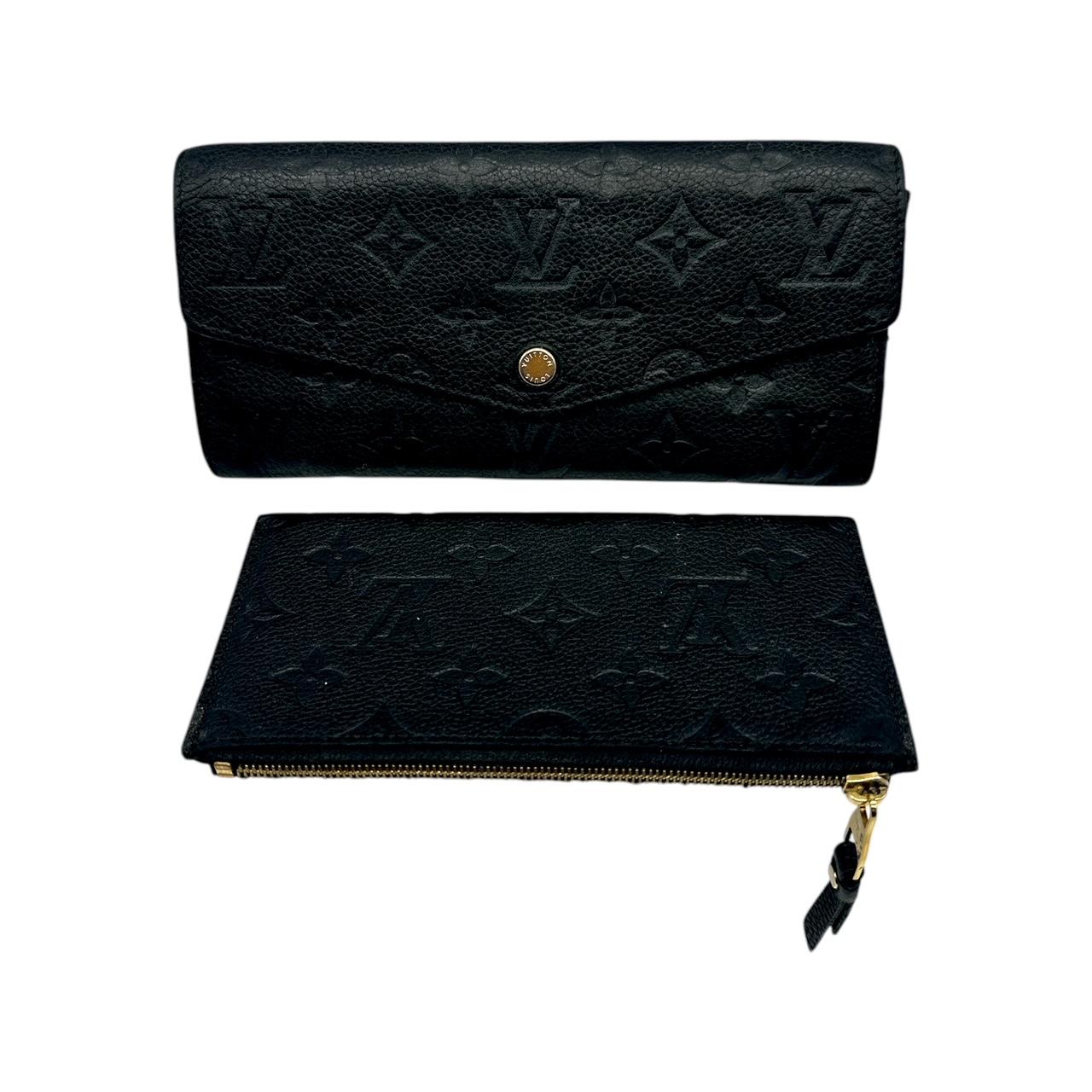 This stylish Louis Vuitton wallet is crafted of monogram embossed leather in classic black. The wallet has a smooth grained leather envelope style flap that opens with a gold snap to an interior of matching leather with patch pockets, card slots and