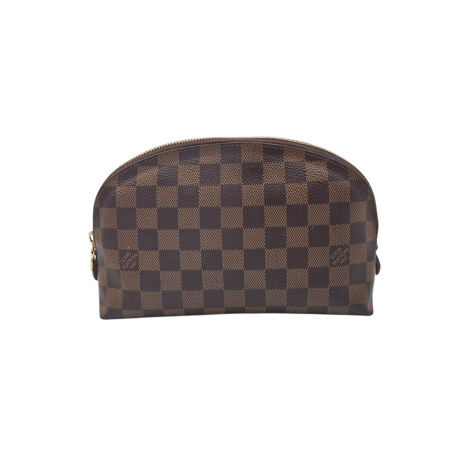 This Louis Vuitton Damier Ebene Cosmetic Pouch is a chic little gem! Made with the classic checked canvas and shiny gold hardware, it’s perfect for keeping your essentials tidy. Inside, a bright red lining and a handy pocket add a pop of fun and