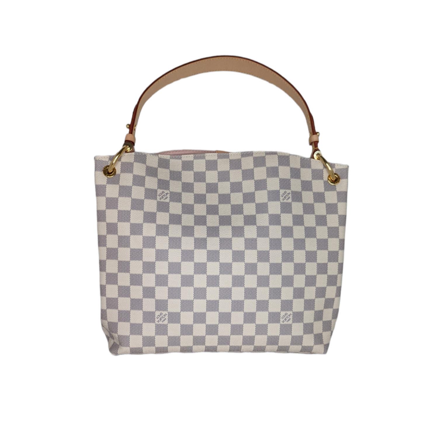 This stylish shoulder bag is finely crafted of Louis Vuitton's signature Damier coated canvas in blue and white. The bag features a flat vachetta leather shoulder strap with polished brass hardware and a magnetic closure. This opens the bag to a