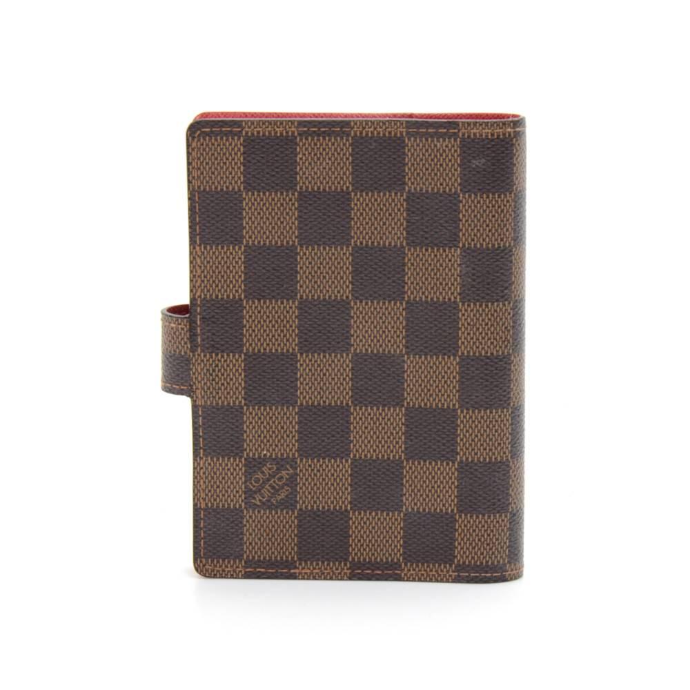 Louis Vuitton Damier Ebene Agenda PM Koala agenda cover. It has 3 card slots, 2 side slip pockets, one Louis Vuitton ruler and one pen holder. Inside is lined with Koala red canvas and has a gold tone 6 small rings to hold your schedule, addresses,