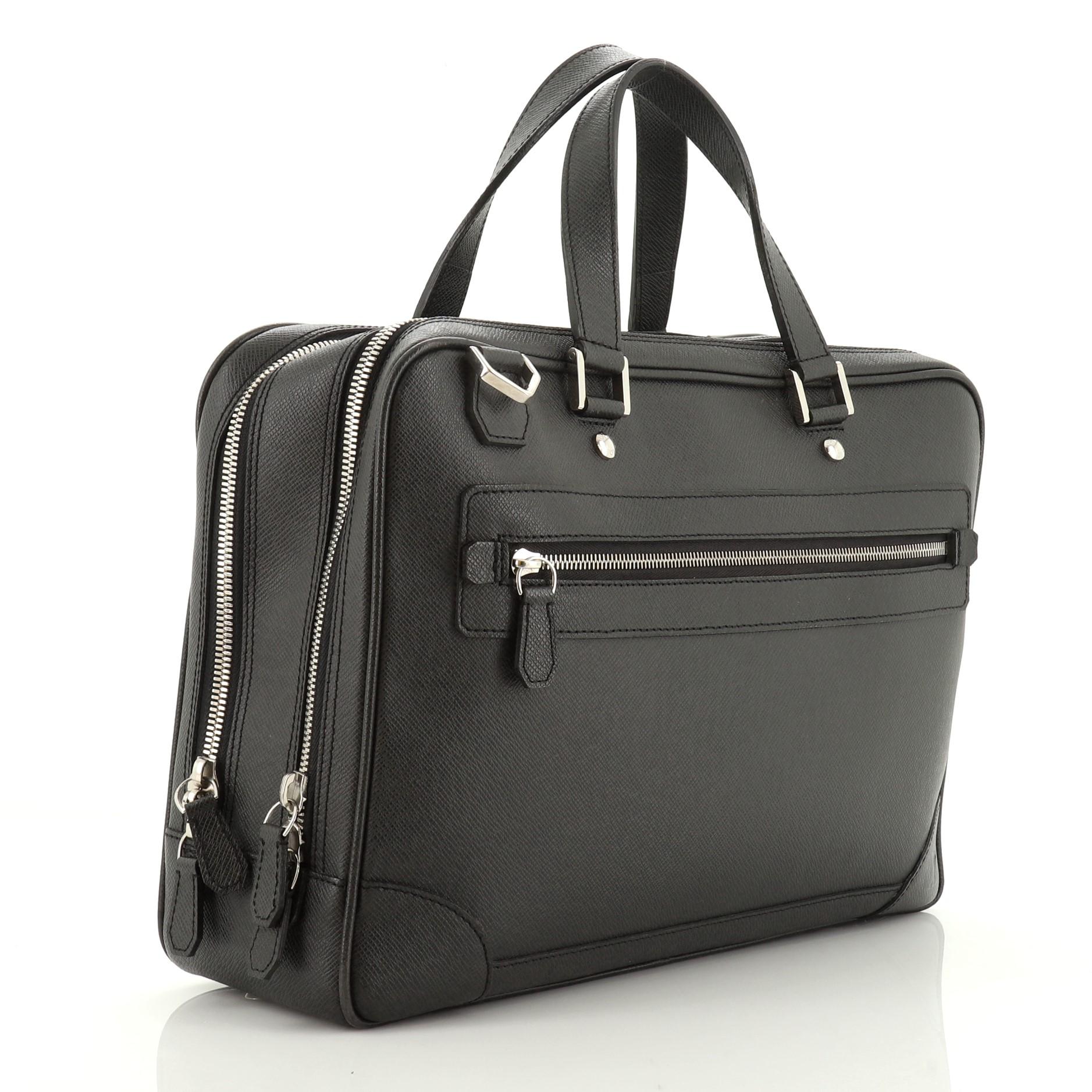 This Louis Vuitton Alexander Briefcase Taiga Leather, crafted in black taiga leather, features dual flat leather handles, exterior zip pocket and silver-tone hardware. Its zip closures open to a two-compartment black fabric interior with slip