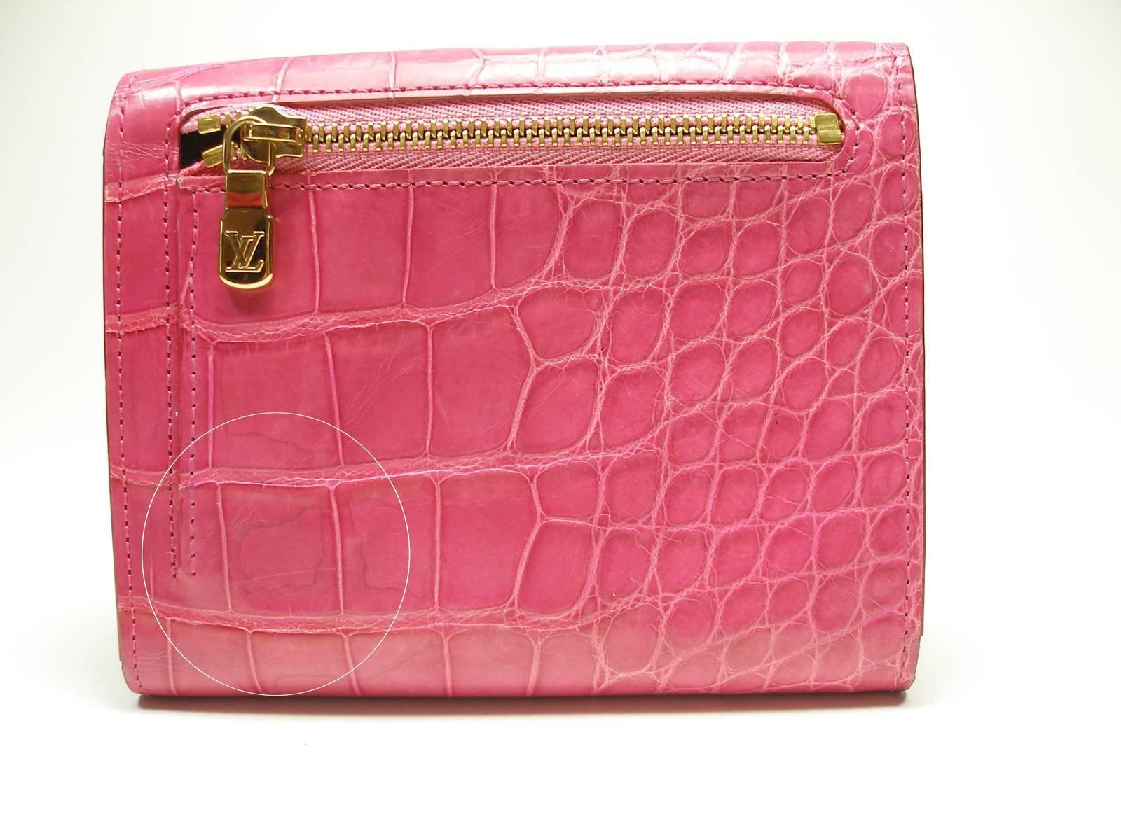  LOUIS VUITTON Alligator Koala Wallet Pink. This stylish wallet is crafted of lovely alligator skin and features a frontal flap with a brass press lock. This opens to a matte chevre goatskin leather interior with card slots, patch pockets, an ID