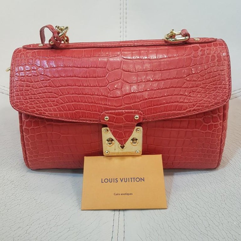 Limited series from the Maison Louis Vuitton, this bag is exceptional for its perfect manufacturing worthy of the great leatherworkers. It is in mat red alligator. The attributes are in golden brass. In perfect condition. It has a leather pouch