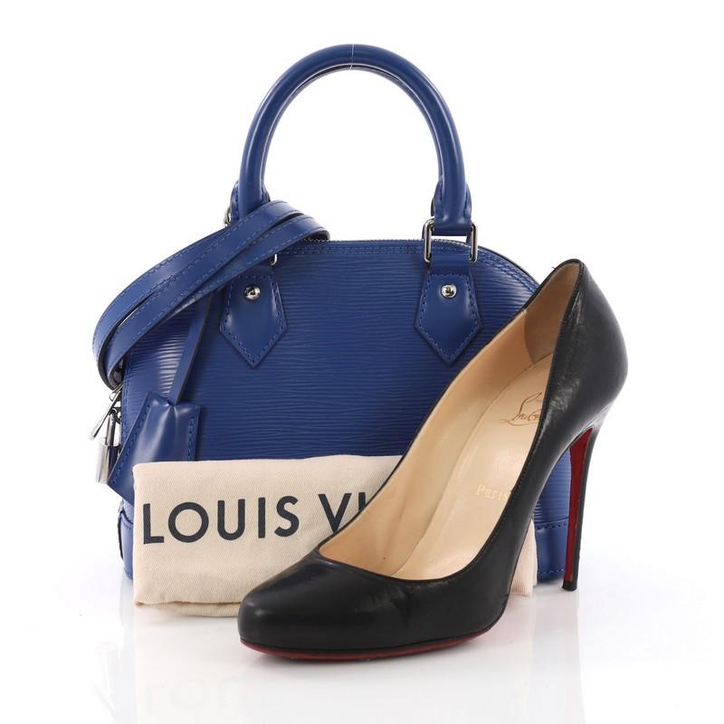 This Louis Vuitton Alma Handbag Epi Leather BB, crafted in blue epi leather, features dual rolled handles, subtle LV logo at the front, and silver-tone hardware. Its zip-around closure opens to a blue microfiber interior with slip pocket.