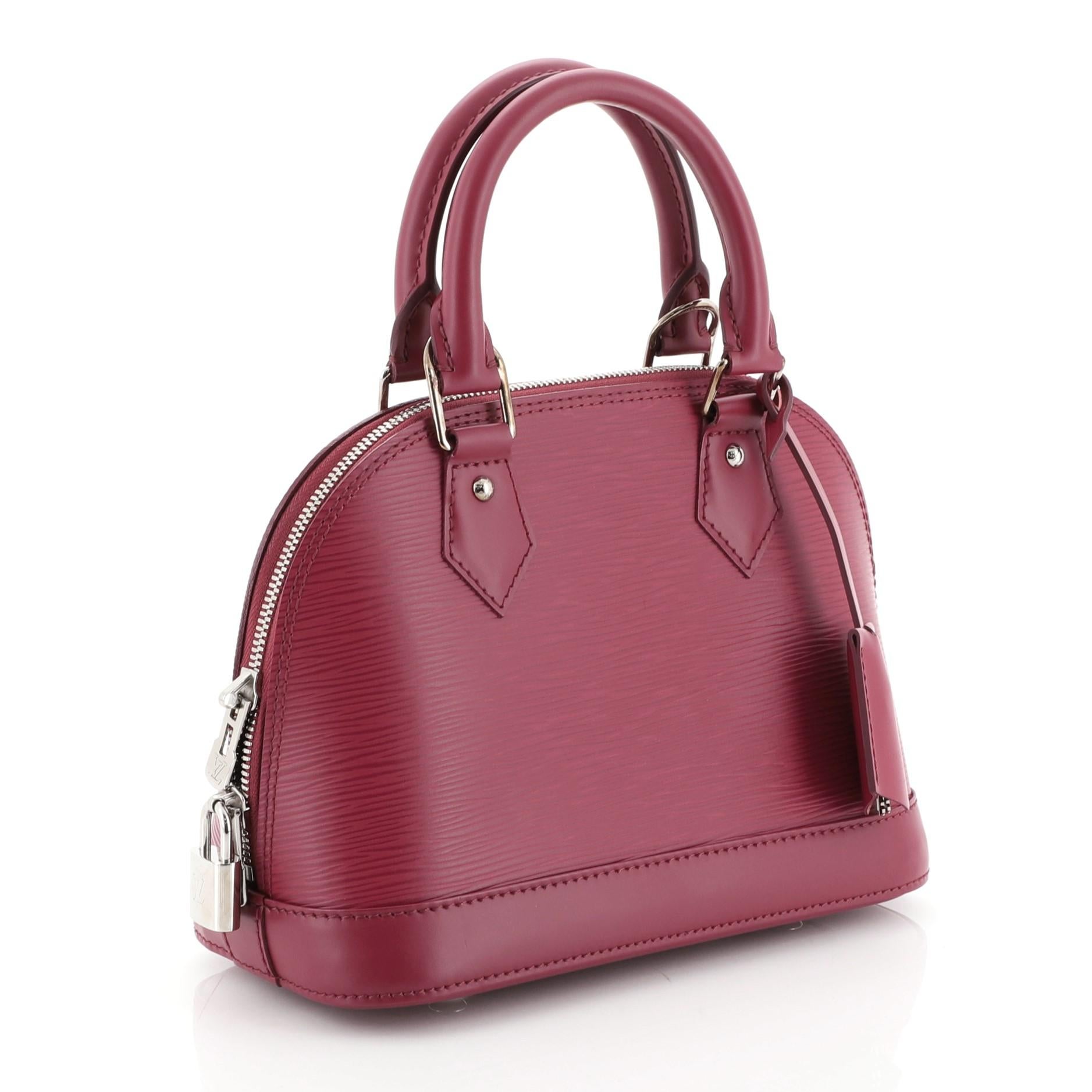 This Louis Vuitton Alma Handbag Epi Leather BB, crafted in purple epi leather, features dual rolled leather handles and silver-tone hardware. Its all-around zip closure opens to a purple microfiber interior with slip pocket. Authenticity code reads: