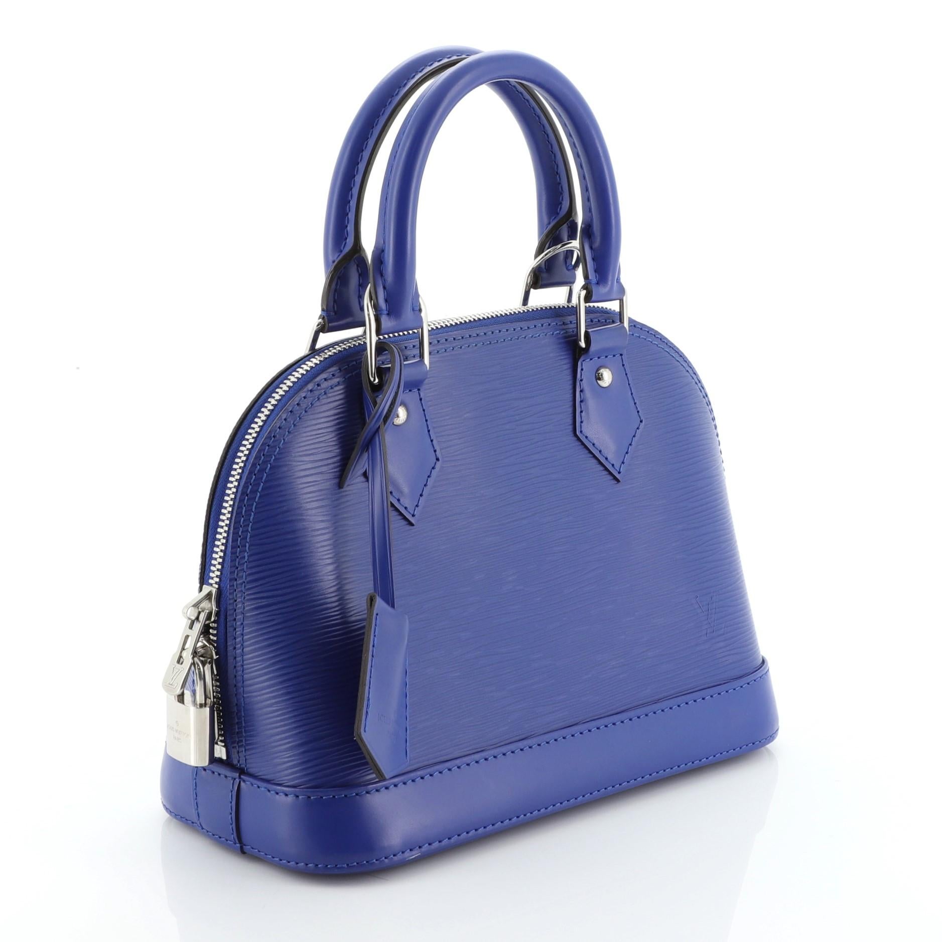 This Louis Vuitton Alma Handbag Epi Leather BB is a classic piece named after Alma Bridge, a span that connects two Parisian neighborhoods. Crafted in blue epi leather, it features dual rolled leather handles and silver-tone hardware. Its all-around