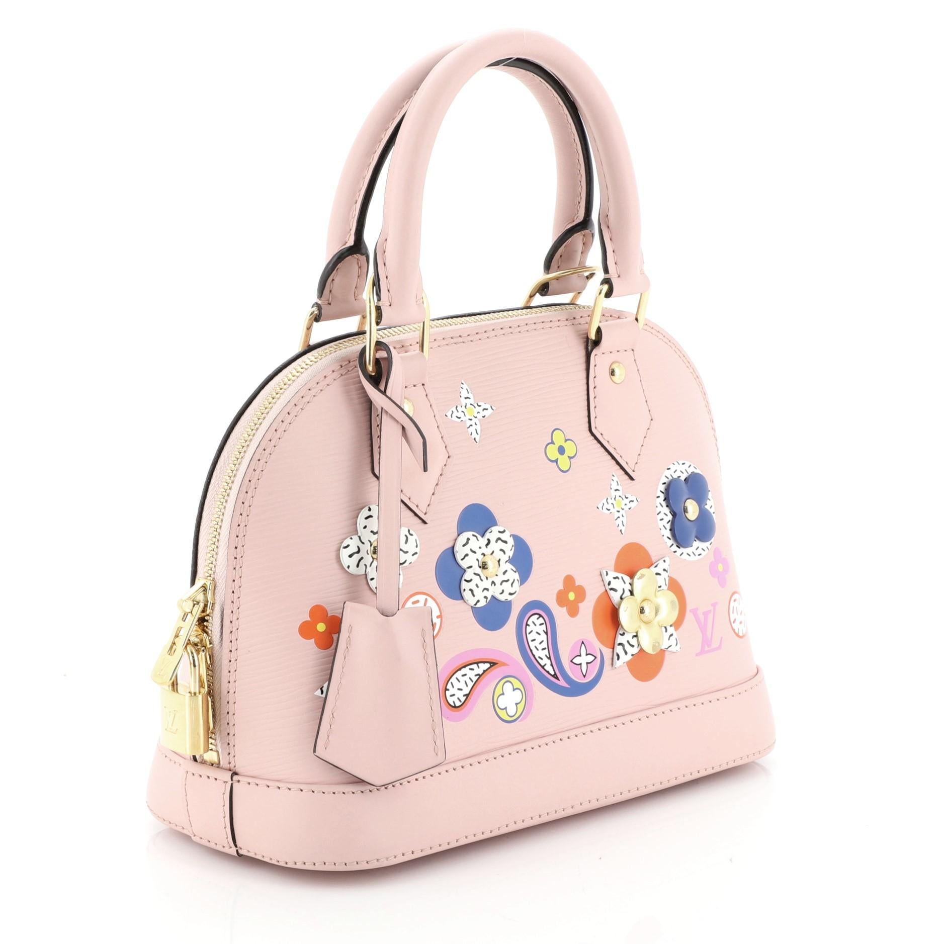 This Louis Vuitton Alma Handbag Limited Edition Floral Patchwork Epi Leather BB, crafted in pink epi leather, features dual rolled handles, floral patchwork detailing and gold-tone hardware. Its zip-around closure opens to a pink microfiber interior