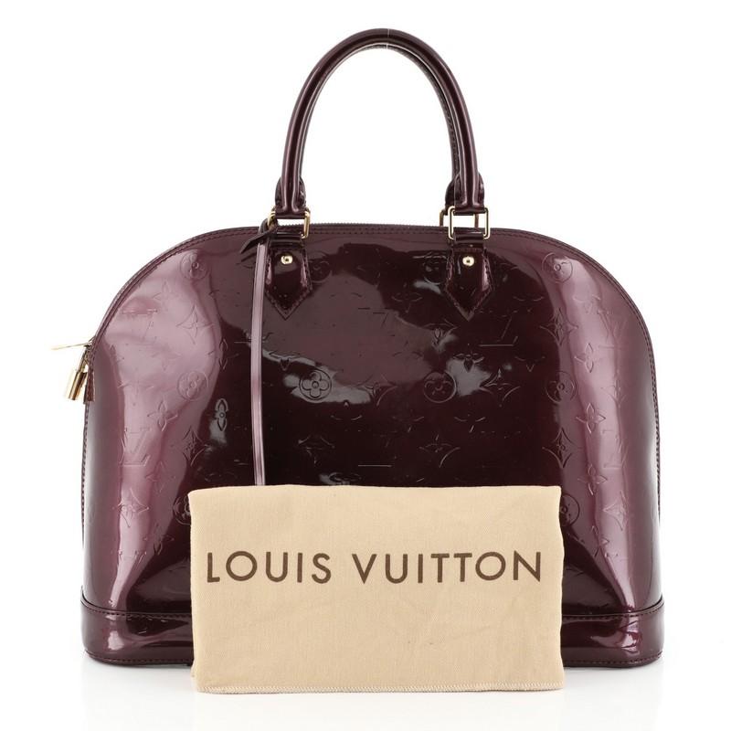 This Louis Vuitton Alma Handbag Monogram Vernis GM, crafted from red monogram vernis leather, features dual rolled handles, protective base studs, and gold-tone hardware. Its two-way zip closure opens to a red fabric interior with slip pockets.