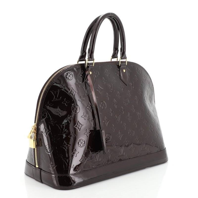 This Louis Vuitton Alma Handbag Monogram Vernis GM, crafted from burgundy monogram vernis leather, features dual rolled handles, protective base studs, and gold-tone hardware. Its two-way zip closure opens to a burgundy fabric interior with slip