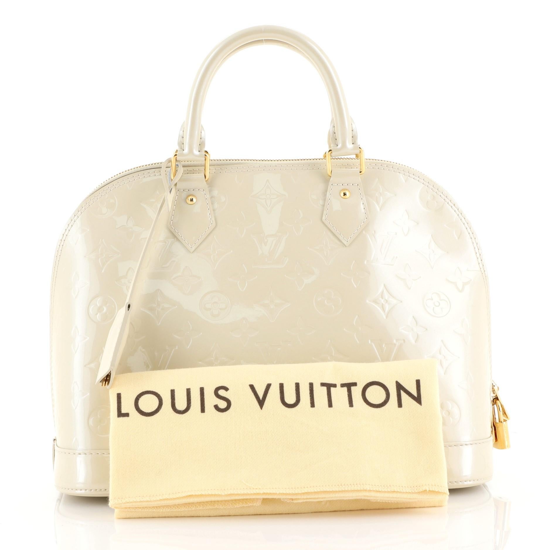 This Louis Vuitton Alma Handbag Monogram Vernis PM, crafted from neutral monogram vernis leather, features dual rolled handles, protective base studs, and gold-tone hardware. Its zip closure opens to a neutral fabric interior with slip pockets.