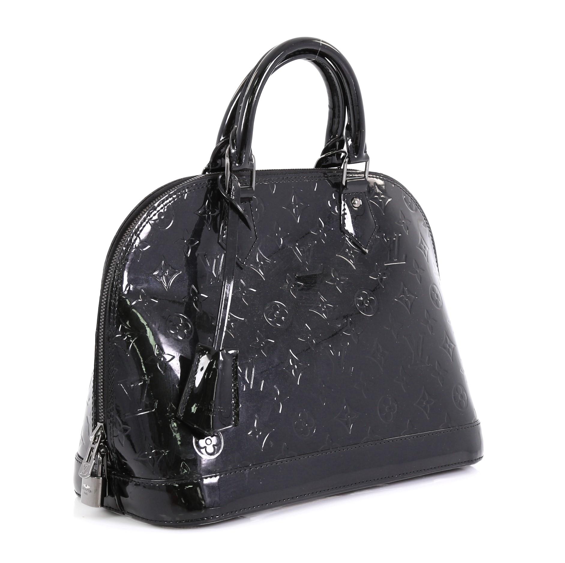 This Louis Vuitton Alma Handbag Monogram Vernis PM, crafted from black monogram vernis leather, features dual rolled handles, protective base studs, and gunmetal-tone hardware. Its zip closure opens to a black fabric interior with slip pockets.