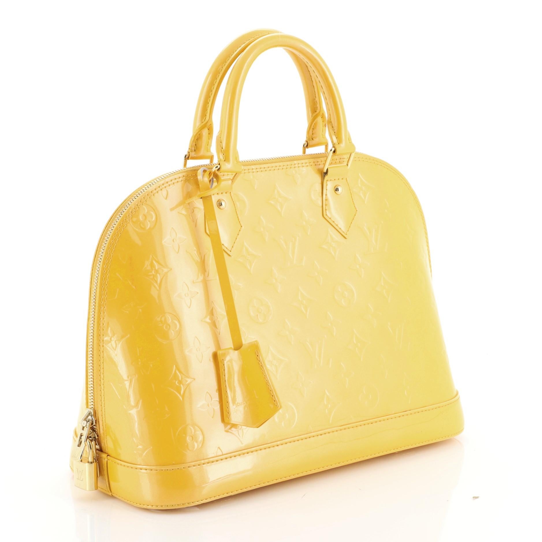This Louis Vuitton Alma Handbag Monogram Vernis PM crafted from yellow monogram vernis leather, features dual rolled handles, protective base studs, and gold-tone hardware. Its zip closure opens to a yellow fabric interior with slip pockets.