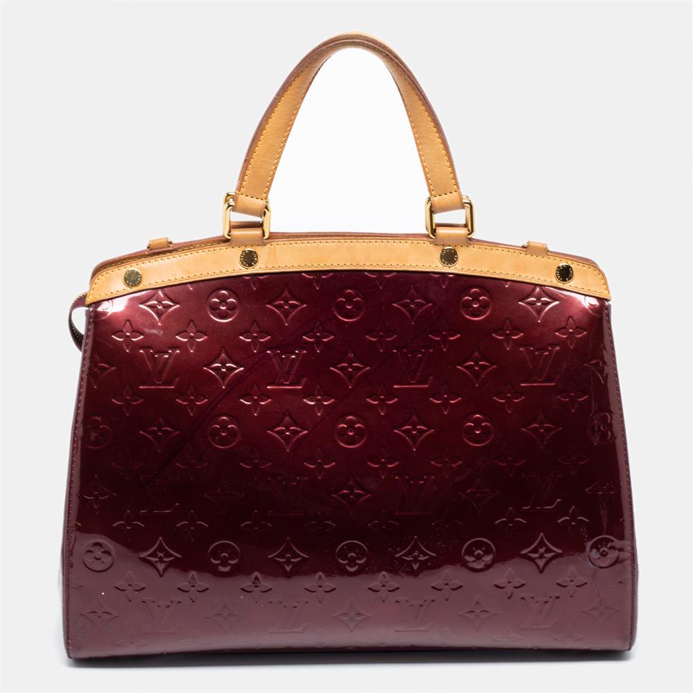 The feminine shape of Louis Vuitton's Brea is inspired by the doctor's bag. Crafted from monogram Vernis in burgundy, the bag has a perfect finish. The fabric interior is spacious and it is secured by a zipper. The bag features double handles,