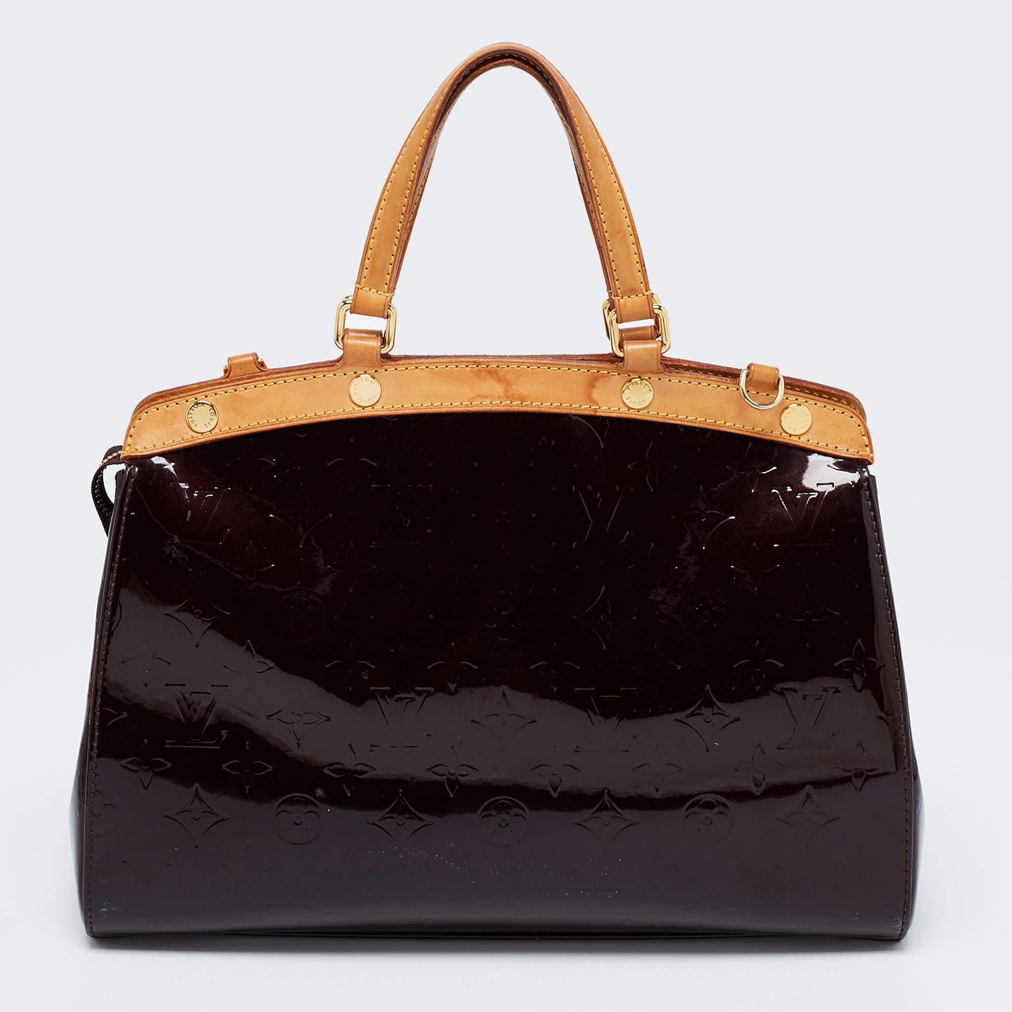 The feminine shape of Louis Vuitton's Brea is inspired by the doctor's bag. Crafted from Monogram Vernis, the bag has a fine finish. The fabric interior is spacious, and it is secured by a zipper. The bag features double handles, a shoulder strap,