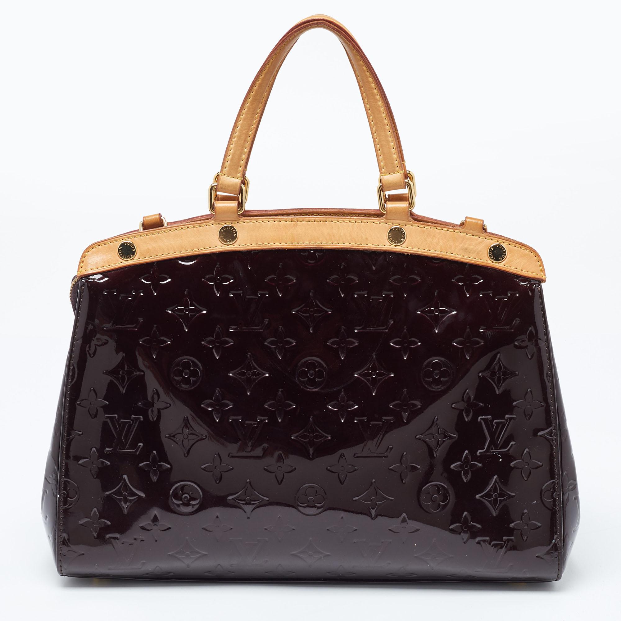 This Brea MM bag from the House of Louis Vuitton will definitely sway you away with its precise shape, style, and design. It is made from Amarante Monogram Vernis into a structured, neat silhouette. It flaunts gold-toned fittings, dual top handles,