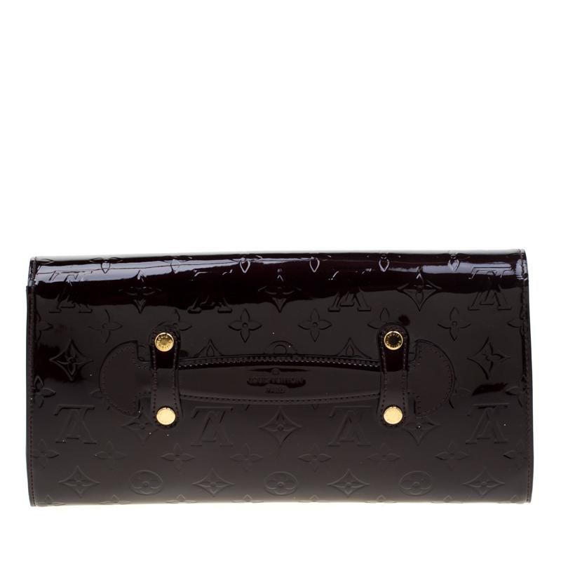 The Vernis range of handbags by Louis Vuitton is famous and sought after by women worldwide. This Robertson clutch has been crafted from patent leather in their signature monogram and styled with a flap that opens to an interior with a well-sized