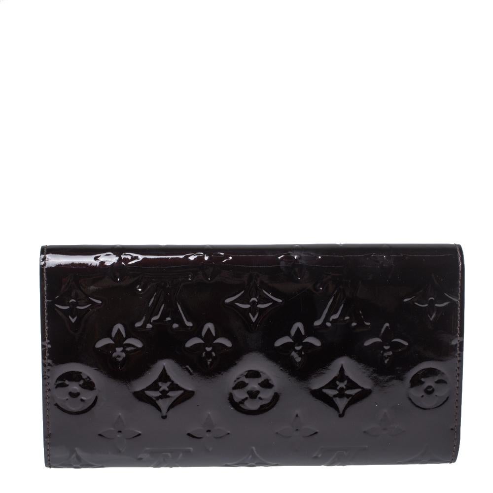 One of the most famous wallets by Louis Vuitton is the Sarah. This one here comes made from Monogram Vernis leather and the button on the flap opens to an interior with multiple card slots and a flap pocket. Perfect in size, this wallet can easily