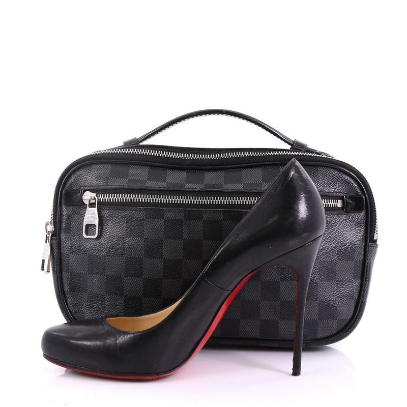 This Louis Vuitton Ambler Bag Damier Graphite, crafted from damier graphite coated canvas, features a leather top handle, adjustable canvas strap, exterior front zip pocket, leather trim, and silver-tone hardware. Its zip closure opens to a black