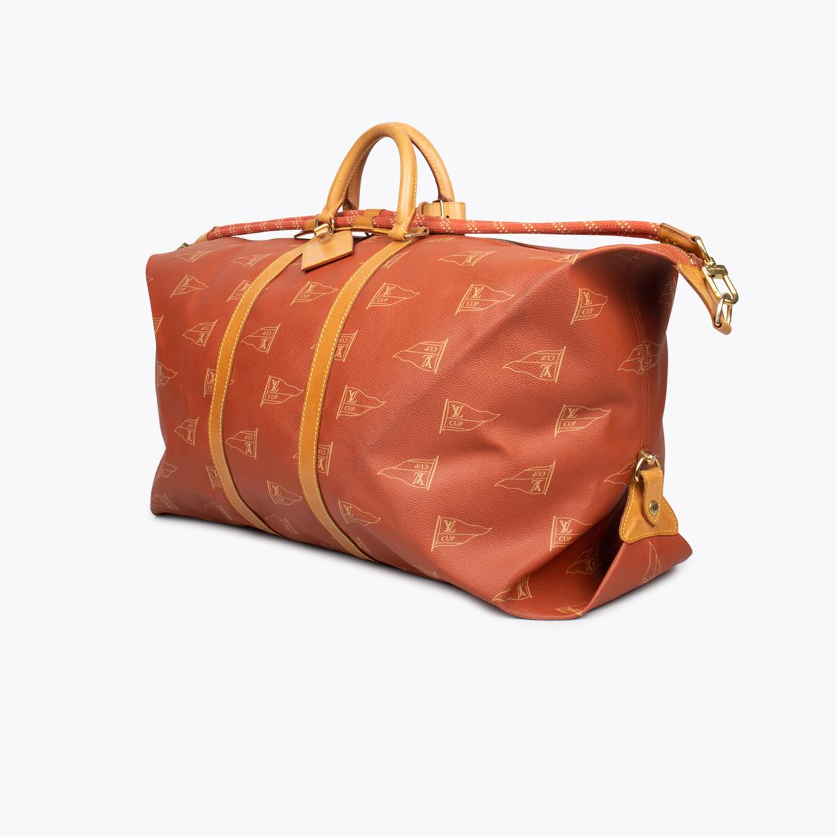 Brick and creme monogram coated canvas Louis Vuitton America's Cup duffle bag with

– Brass hardware
– Tan vachetta leather trim
– Dual rolled handles
– Detachable woven shoulder strap, brown canvas interior lining, single interior slit pocket and
