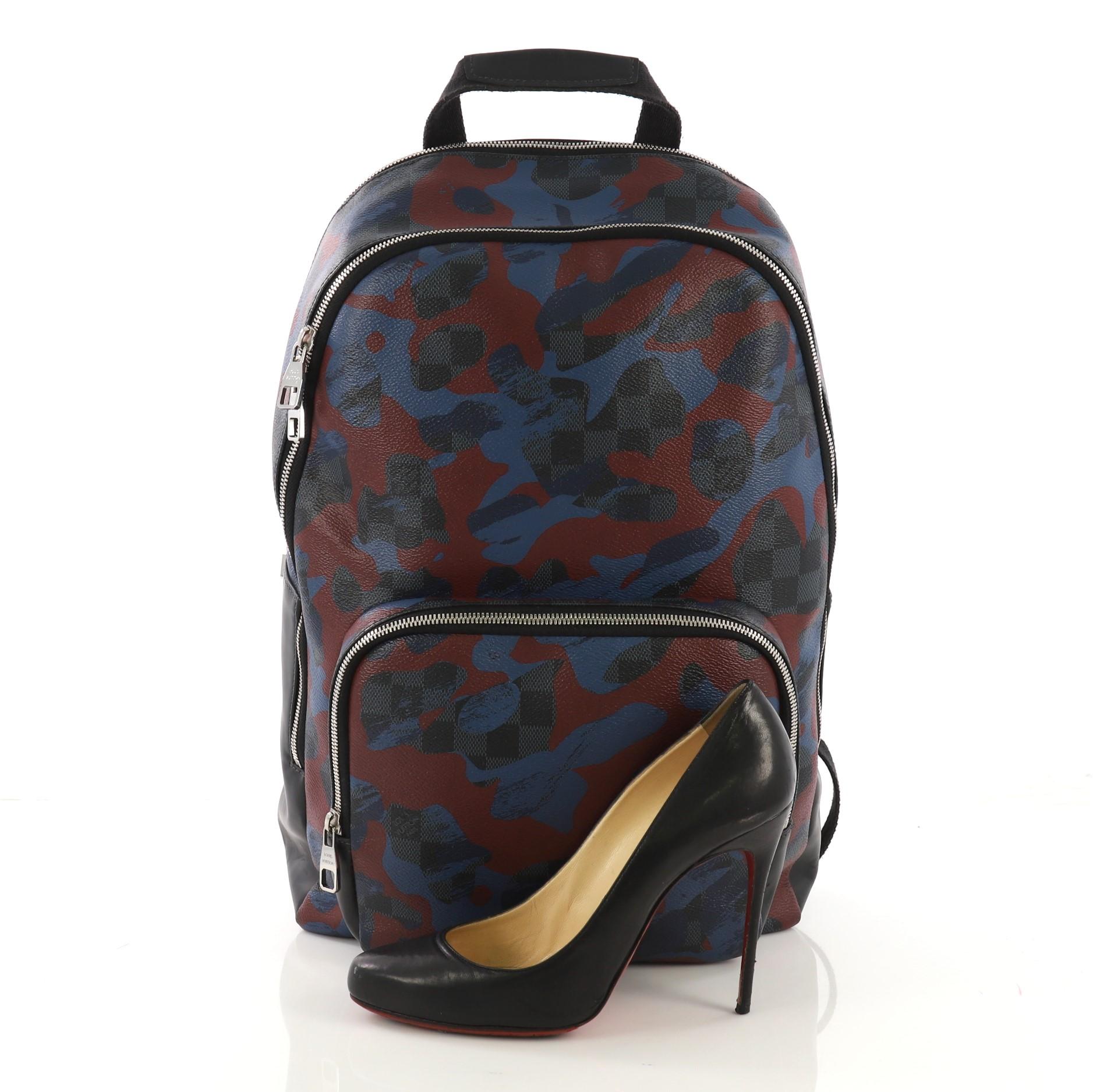 This Louis Vuitton Andy Backpack Limited Edition Camouflage Damier Cobalt, crafted in blue camouflage damier cobalt coated canvas, features a canvas top handle, padded backpack straps, exterior front zip pocket, exterior back padded laptop