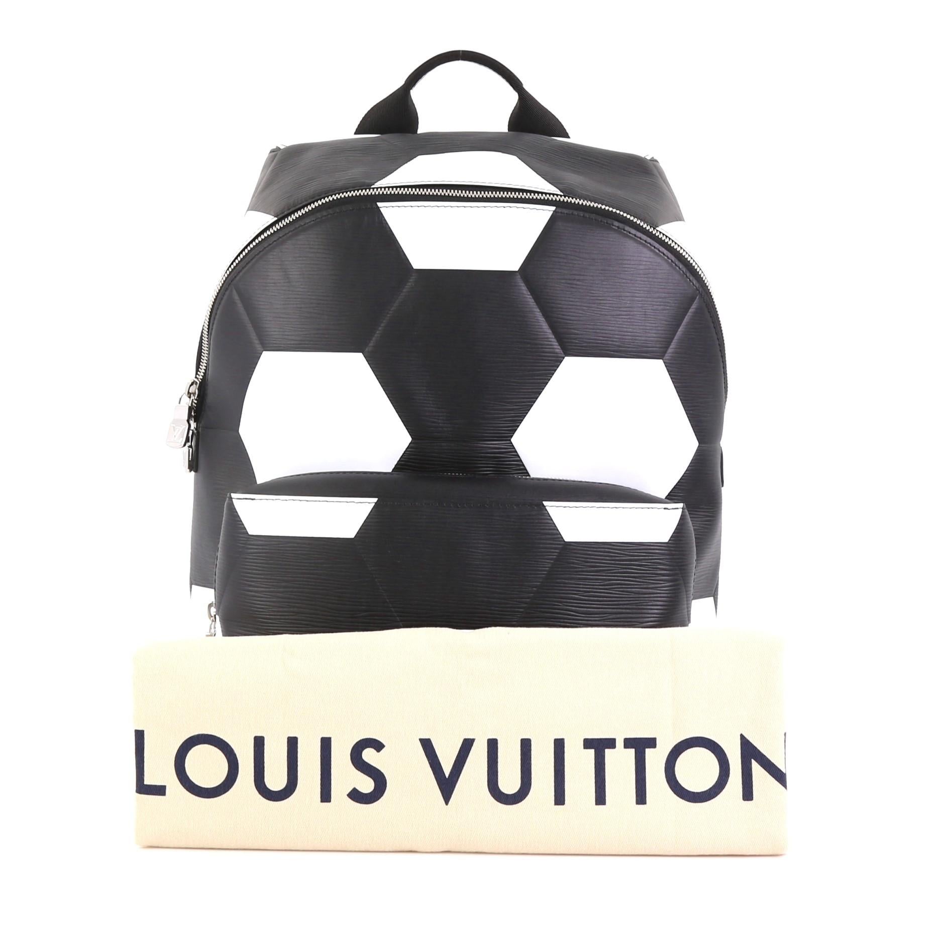This Louis Vuitton Apollo Backpack Limited Edition FIFA World Cup Epi Leather, crafted from black and white epi leather, features a top handle, adjustable back straps, hexagonal pattern of footballs, exterior front zip pocket, and silver-tone