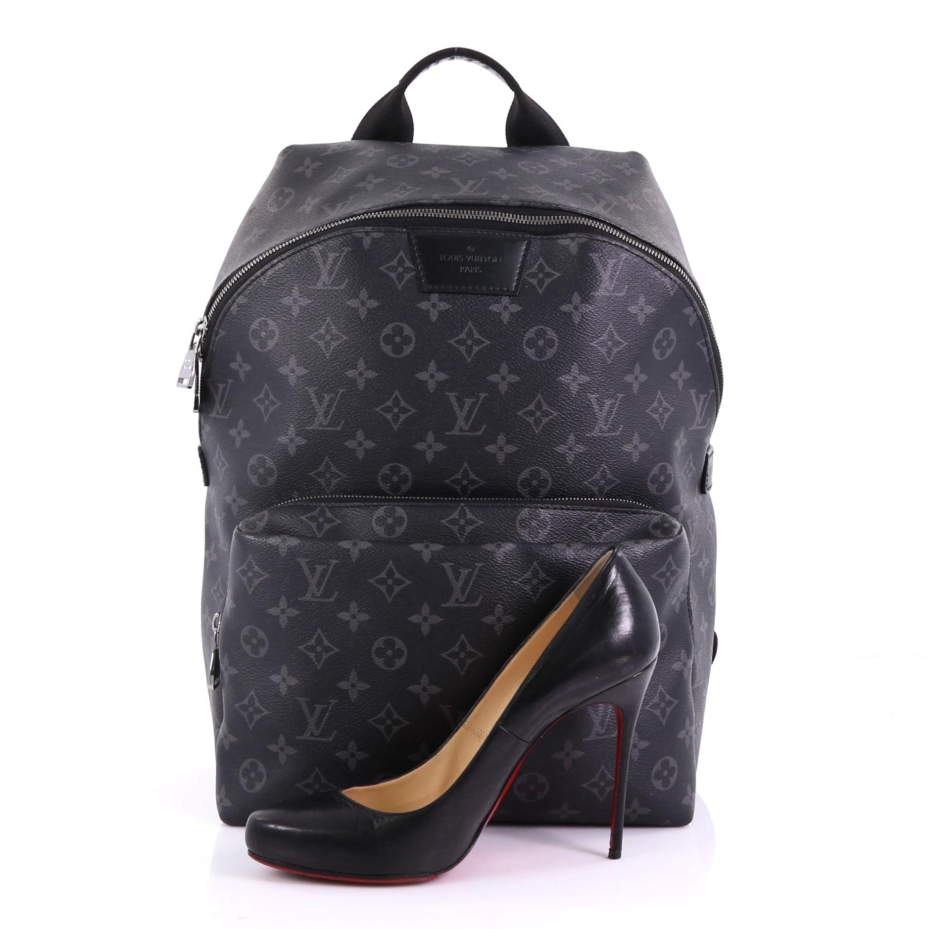 This Louis Vuitton Apollo Backpack Monogram Eclipse Canvas, crafted from black monogram eclipse coated canvas, features a top handle, adjustable back straps, exterior front zip compartment, and silver-tone hardware. Its two-way zip closure opens to