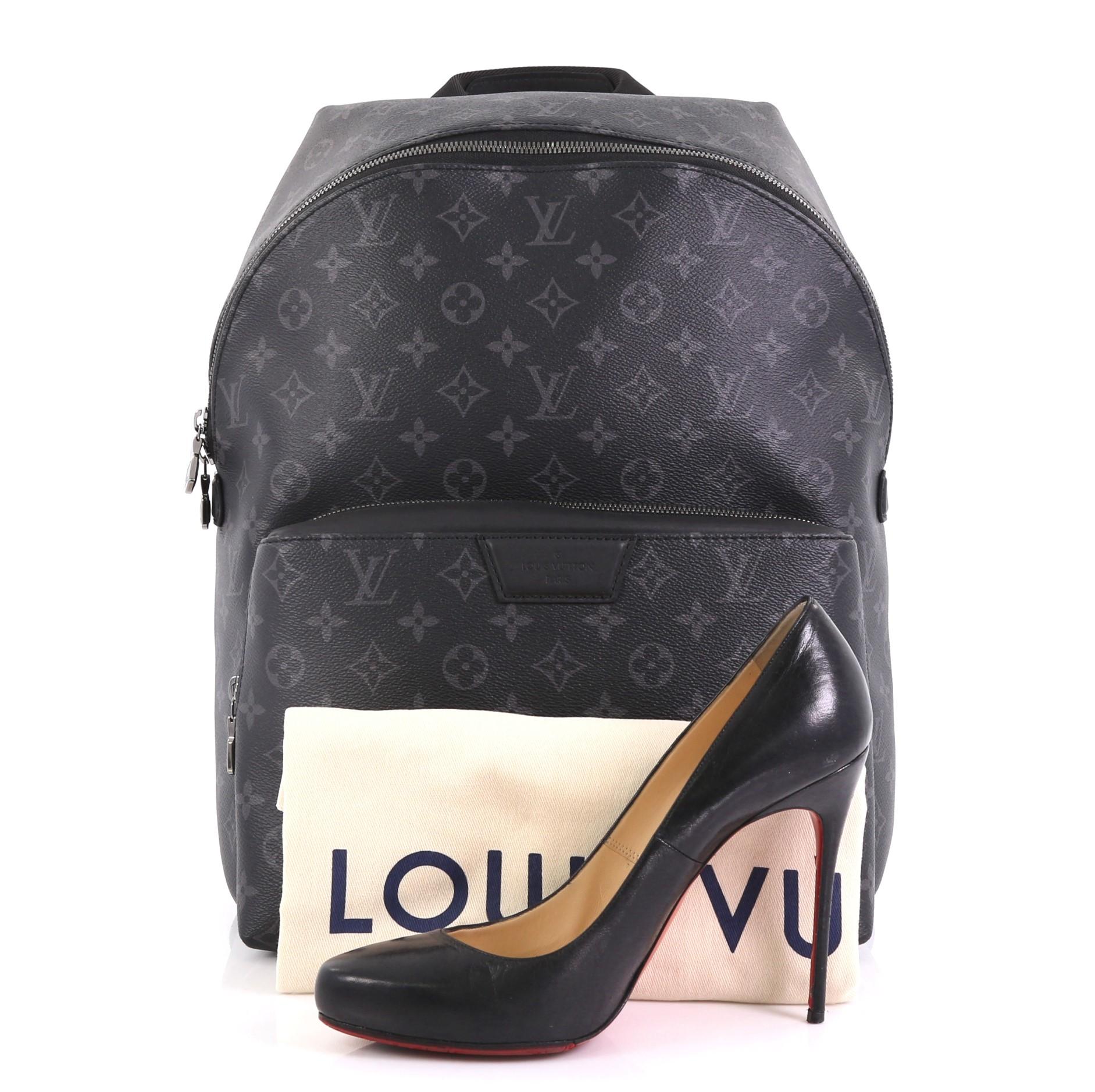 This Louis Vuitton Apollo Backpack Monogram Eclipse Canvas, crafted from black monogram eclipse coated canvas, features a top handle, adjustable back straps, exterior front zip compartment, and gunmetal-tone hardware. Its two-way zip closure opens