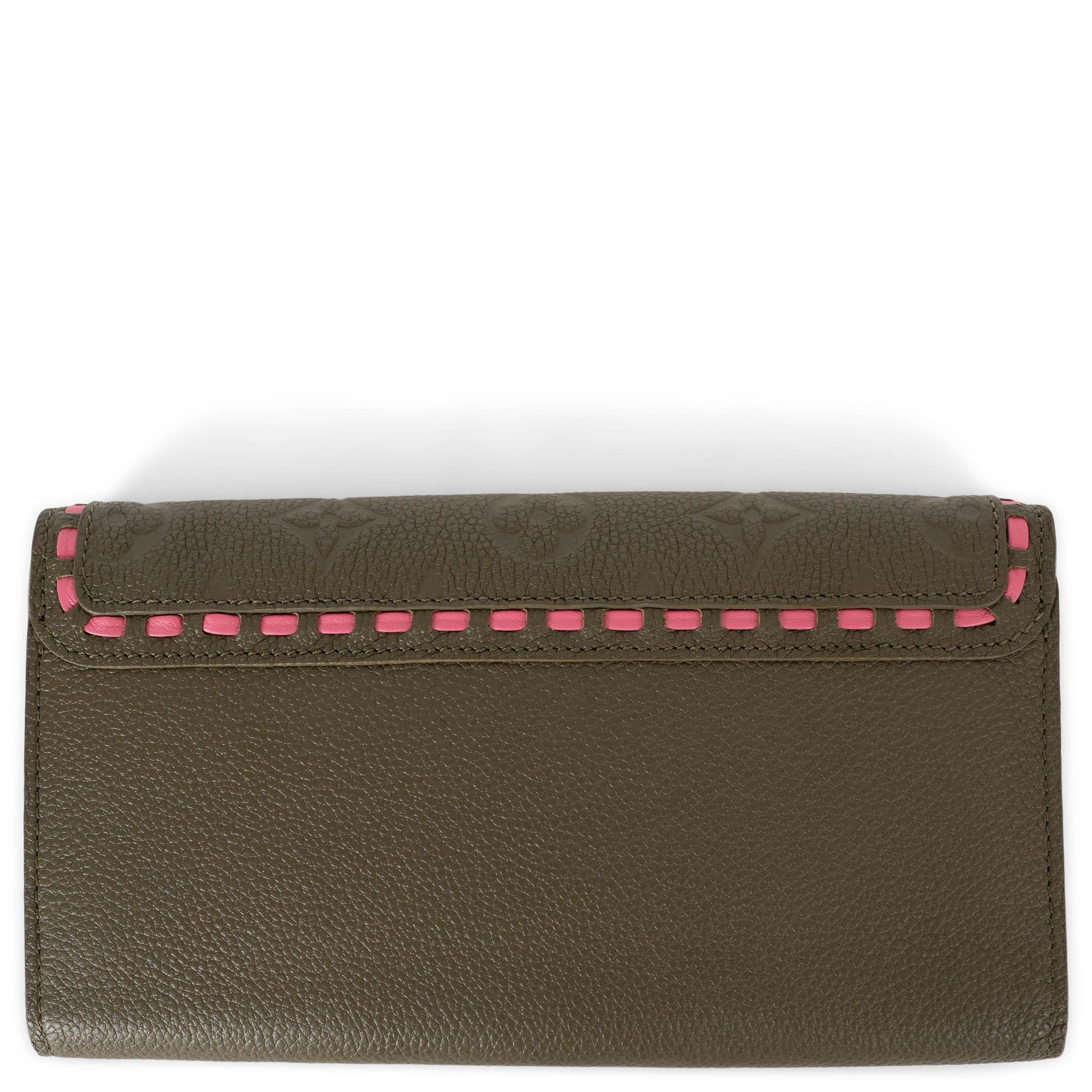This 100% authentic Louis Vuitton Sarah wallet in army green leather features a Monogram Empreinte flap with striking bright pink stitching detail, adding a pop of color to its classic design. It opens with a snap-button on the front, revealing an