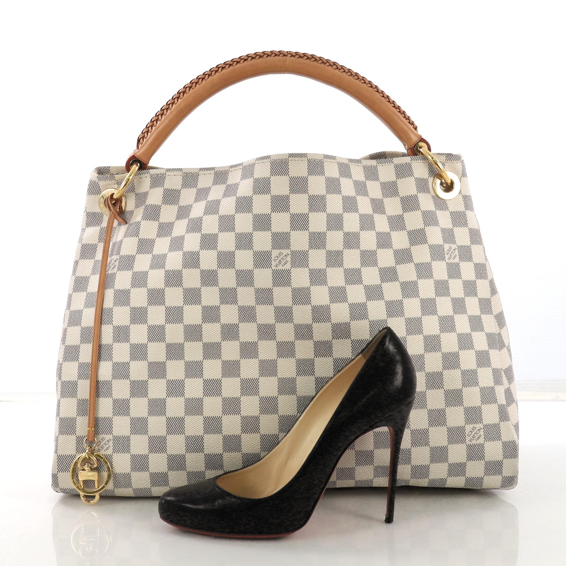 This Louis Vuitton Artsy Handbag Damier MM, crafted from damier azur coated canvas, features a single looped hand-crafted leather handle, protective base studs, and gold-tone hardware. Its wide open top showcases a beige microfiber interior with zip