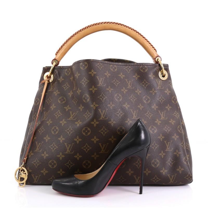 This Louis Vuitton Artsy Handbag Monogram Canvas MM, crafted from brown monogram coated canvas, features a rolled leather handle with braided detailing, protective base studs, and gold-tone hardware. It opens to a beige fabric interior with side zip