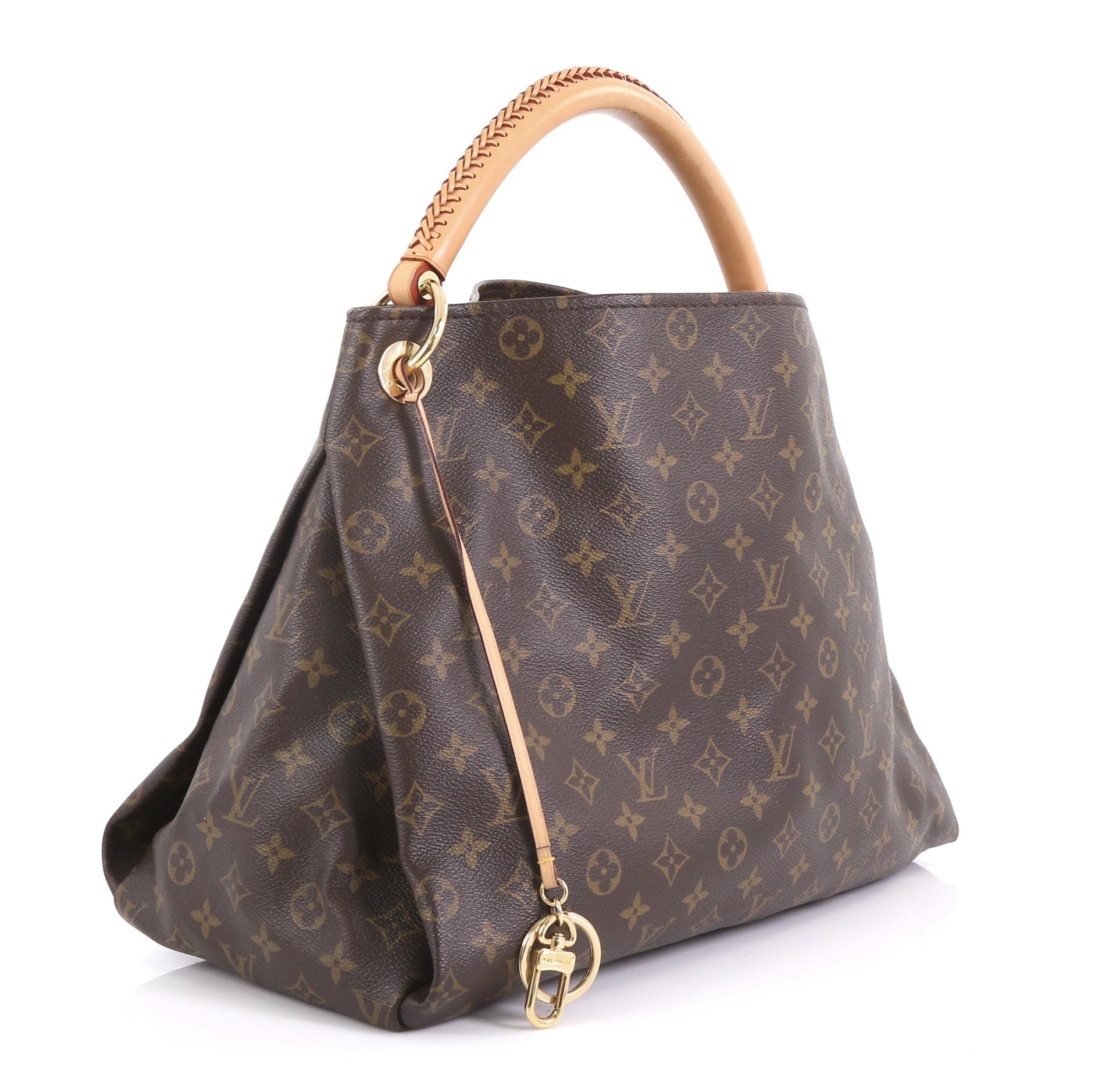 This Louis Vuitton Artsy Handbag Monogram Canvas MM, crafted from brown monogram coated canvas, features a rolled leather handle with braided detailing, protective base studs, and gold-tone hardware. It opens to a beige microfiber interior with side