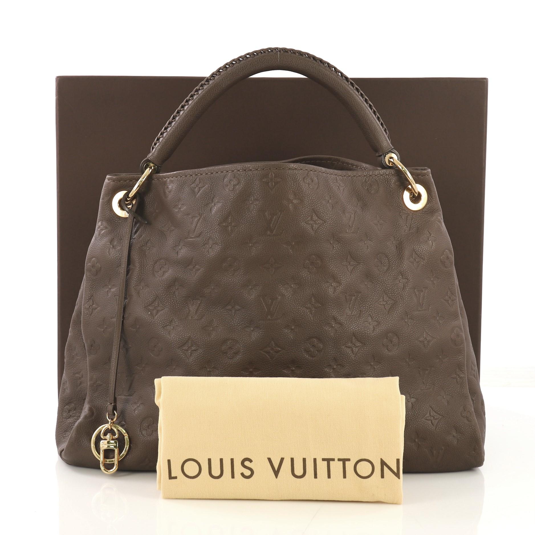 This Louis Vuitton Artsy Handbag Monogram Empreinte Leather MM, crafted from brown monogram empreinte leather, features a single looped braided top handle, protective base studs, and gold-tone hardware. Its wide open top showcases a brown fabric