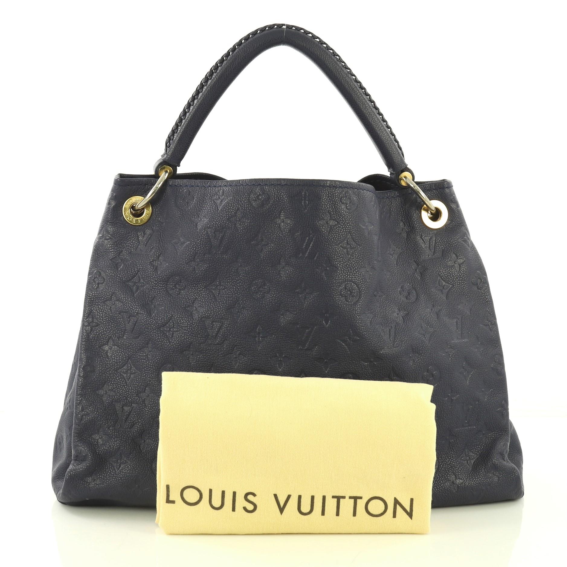 This Louis Vuitton Artsy Handbag Monogram Empreinte Leather MM, crafted from navy blue monogram empreinte leather, features a single looped braided top handle, protective base studs, and gold-tone hardware. Its wide open top showcases a navy blue