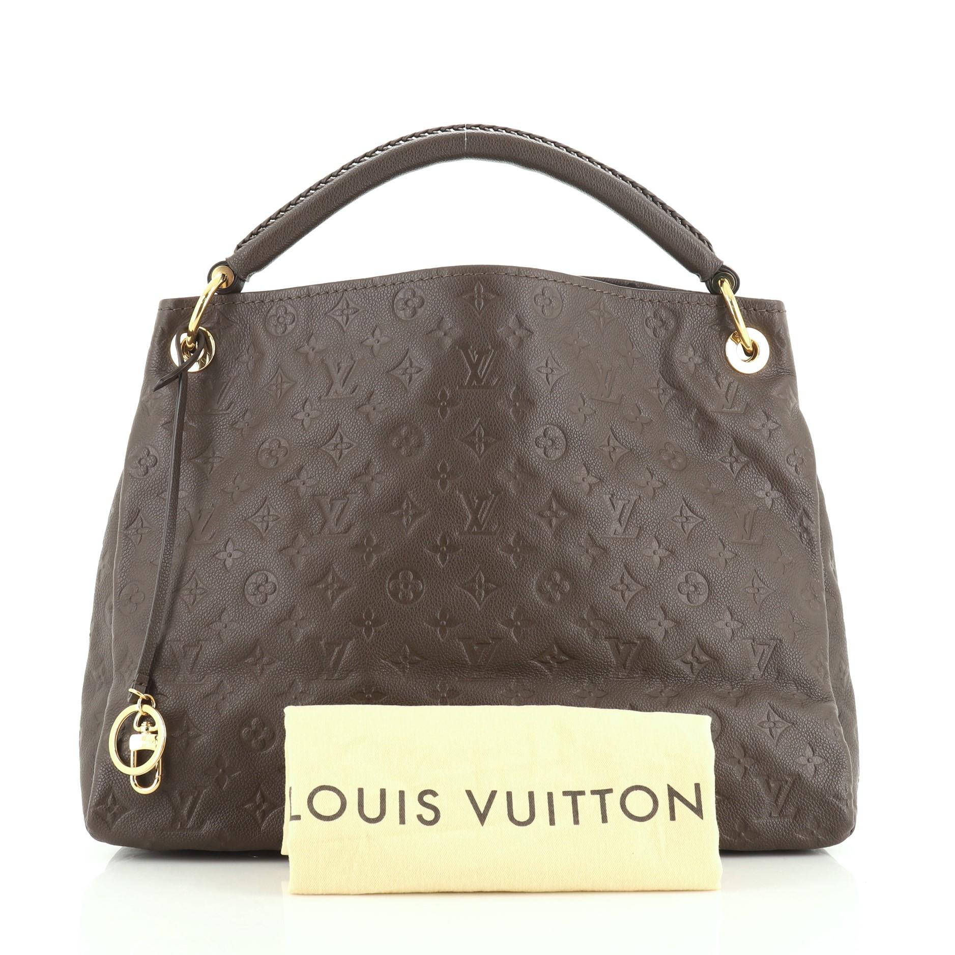 This Louis Vuitton Artsy Handbag Monogram Empreinte Leather MM, crafted from brown monogram empreinte leather, features a single looped braided top handle, protective base studs, and gold-tone hardware. Its wide open top showcases a brown fabric