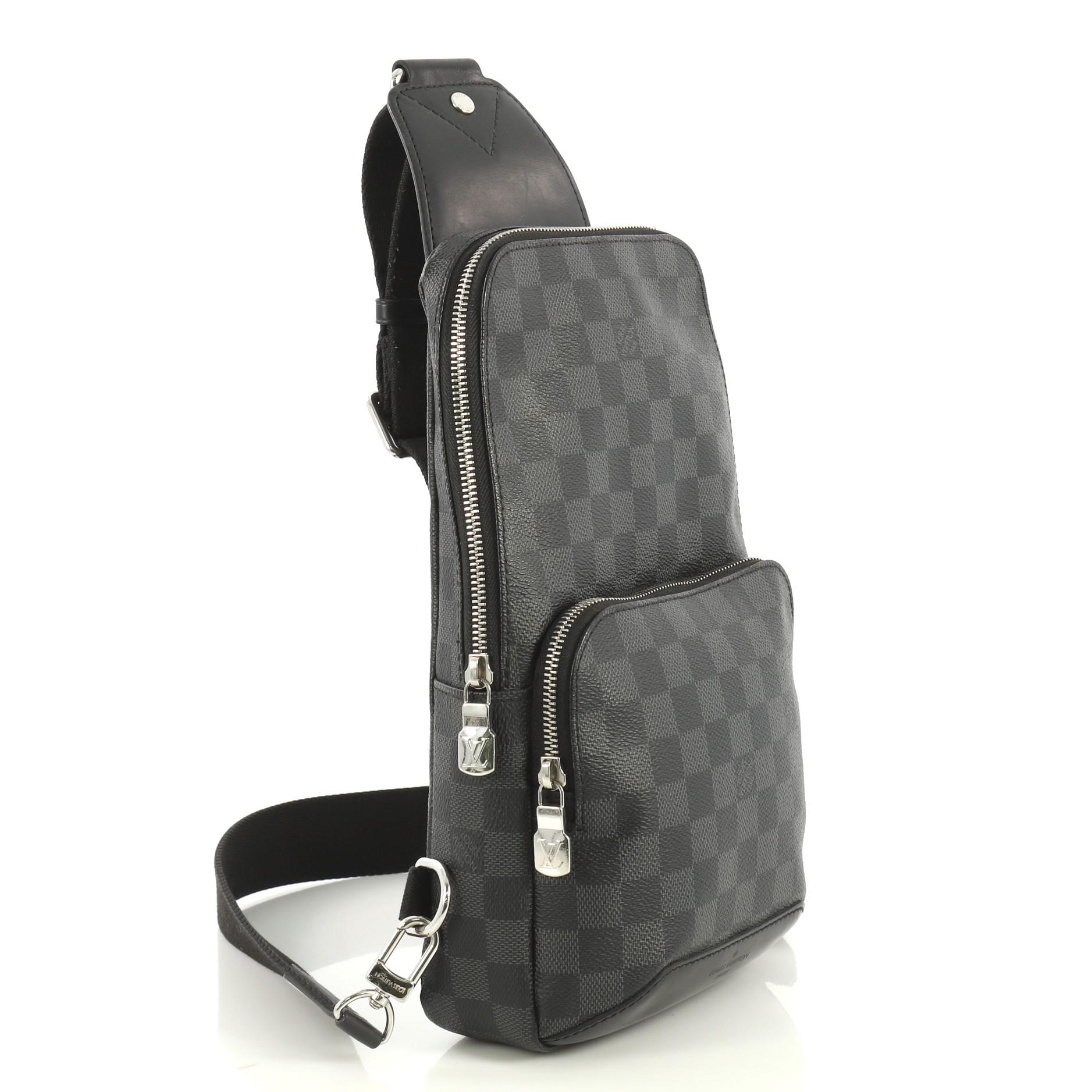 This Louis Vuitton Avenue Sling Bag Damier Graphite, crafted from damier graphite coated canvas, features an adjustable fabric strap, exterior front zip pocket, and silver-tone hardware. Its zip closure opens to a black fabric interior with slip